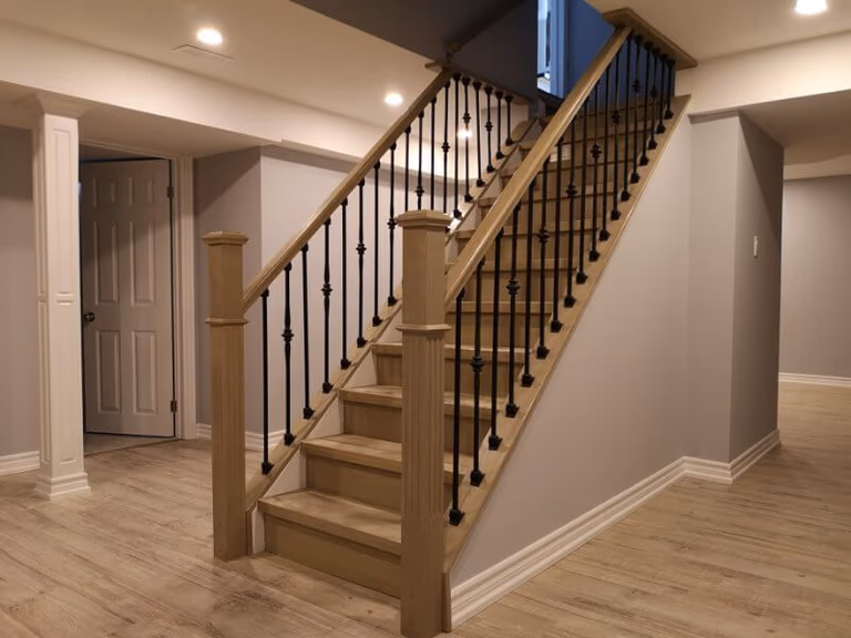This Markham basement renovation project showcases a modern staircase upgrade with natural wood steps, black iron balusters, and newly installed light-toned flooring. Completed by a professional Toronto renovation company, the finished basement features improved layout flow, clean finishes, and a bright, comfortable living space ideal for modern family use.