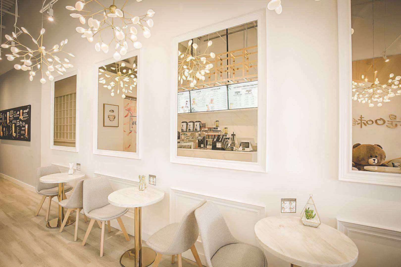 This Toronto bubble tea shop renovation showcases a modern and elegant customer seating area designed to enhance comfort and visual appeal. Featuring custom wall panel detailing, decorative mirrors, warm wood flooring, designer lighting fixtures, and marble-style café tables, the space creates a bright and inviting atmosphere for customers to relax and enjoy their drinks. The layout maximizes seating capacity while maintaining smooth customer flow and an upscale café experience. Completed by a professional Toronto renovation company, this commercial interior project highlights quality craftsmanship, functional space planning, and stylish design tailored for high-traffic milk tea and dessert shop environments.