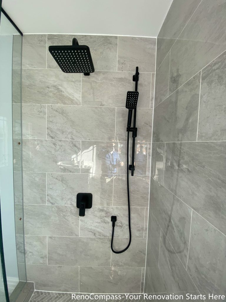 This Thornhill bathroom renovation features a compact walk-in shower enclosed with frameless glass, maximizing visual openness within a narrow layout. Large-format gray wall tiles combined with a herringbone-patterned shower base add texture and depth, while matte black shower fixtures provide a modern, cohesive finish. The clean layout and glass enclosure improve brightness, circulation, and daily functionality, making the space well-suited for guest or secondary bathroom use.