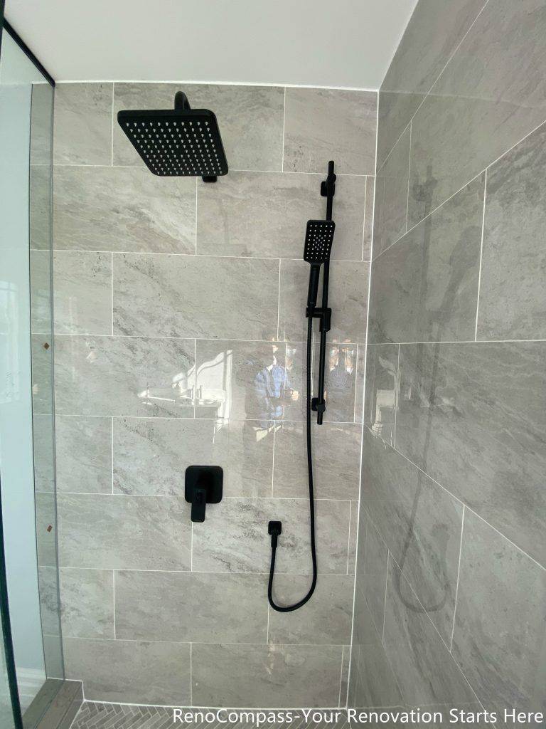 This Thornhill bathroom renovation features a compact walk-in shower enclosed with frameless glass, maximizing visual openness within a narrow layout. Large-format gray wall tiles combined with a herringbone-patterned shower base add texture and depth, while matte black shower fixtures provide a modern, cohesive finish. The clean layout and glass enclosure improve brightness, circulation, and daily functionality, making the space well-suited for guest or secondary bathroom use.