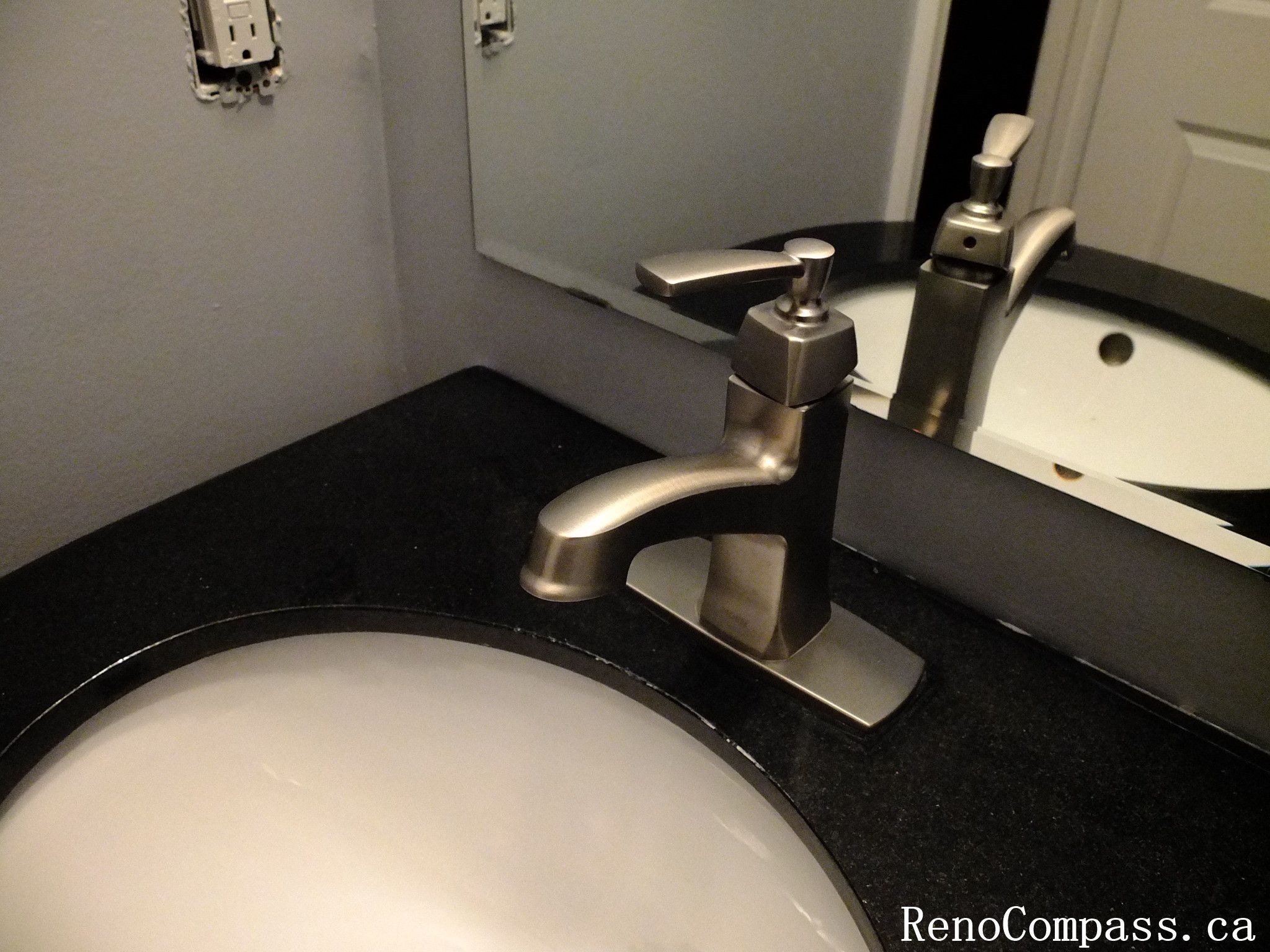 Close-up view of a stylish bathroom renovation in Richmond Hill featuring a brushed nickel faucet, black granite countertop, and modern under-mount sink. This sleek powder room design highlights elegant craftsmanship by RenoCompass.ca home renovation professionals.