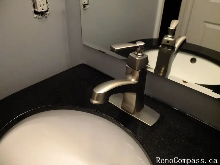 Close-up view of a stylish bathroom renovation in Richmond Hill featuring a brushed nickel faucet, black granite countertop, and modern under-mount sink. This sleek powder room design highlights elegant craftsmanship by RenoCompass.ca home renovation professionals.