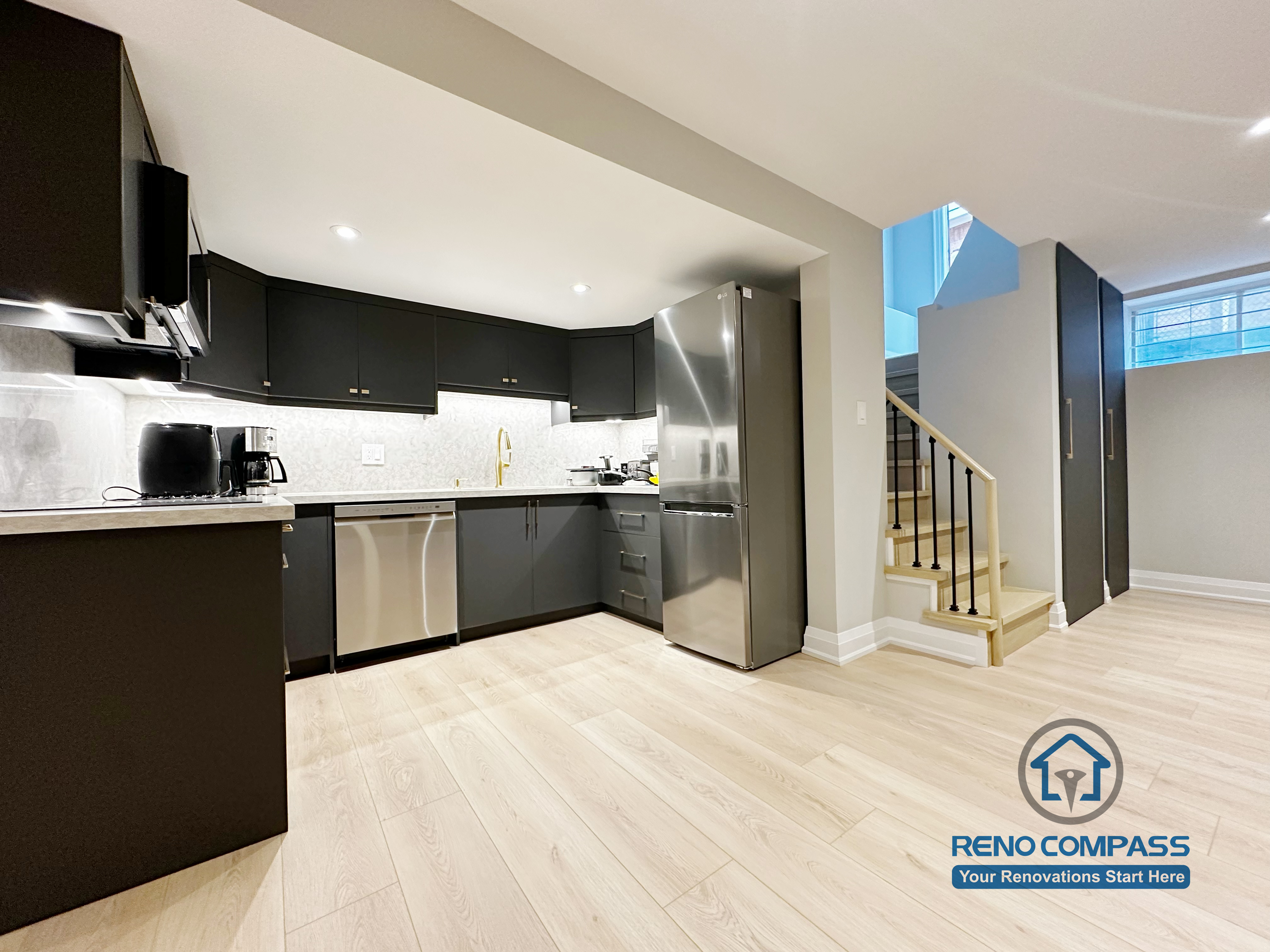 Basement renovation in Richmond Hill featuring a modern kitchenette with matte black cabinetry, stainless steel appliances, quartz-style countertops, and efficient space planning for daily use.