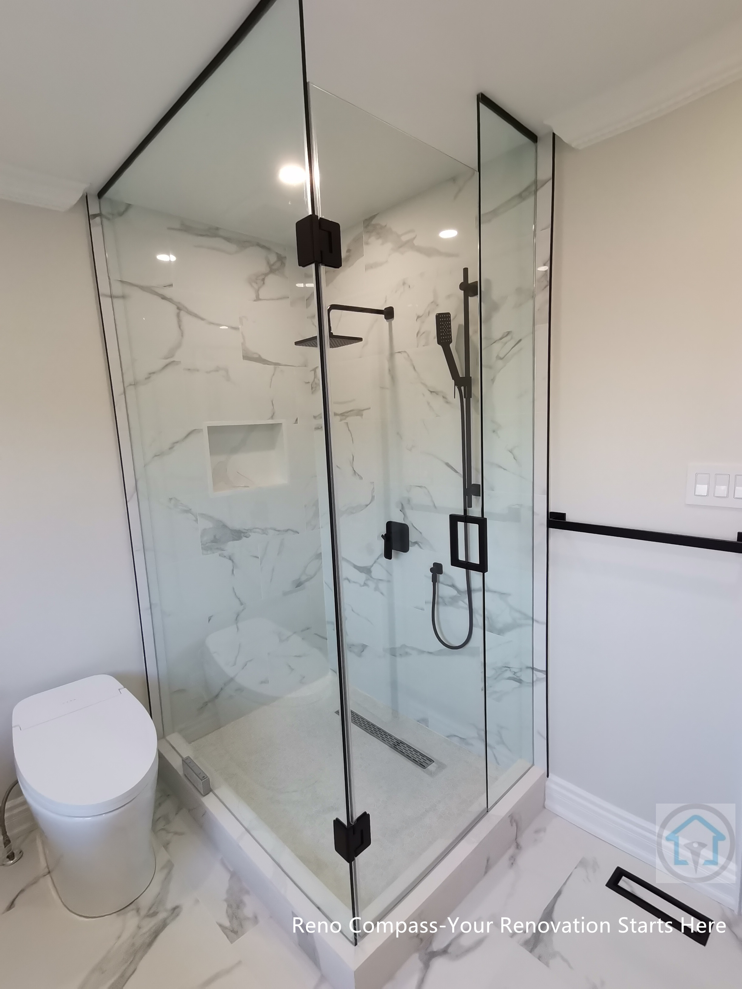 This Thornhill bathroom renovation features a glass-enclosed shower with marble-style wall tiles, modern black fixtures, and a built-in niche for storage. The clean layout integrates the shower area seamlessly with the rest of the bathroom, creating a bright, functional, and well-balanced space for everyday use.