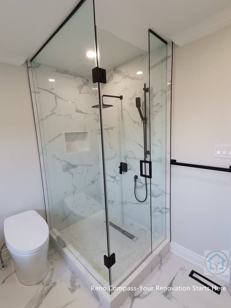 This Thornhill bathroom renovation features a glass-enclosed shower with marble-style wall tiles, modern black fixtures, and a built-in niche for storage. The clean layout integrates the shower area seamlessly with the rest of the bathroom, creating a bright, functional, and well-balanced space for everyday use.