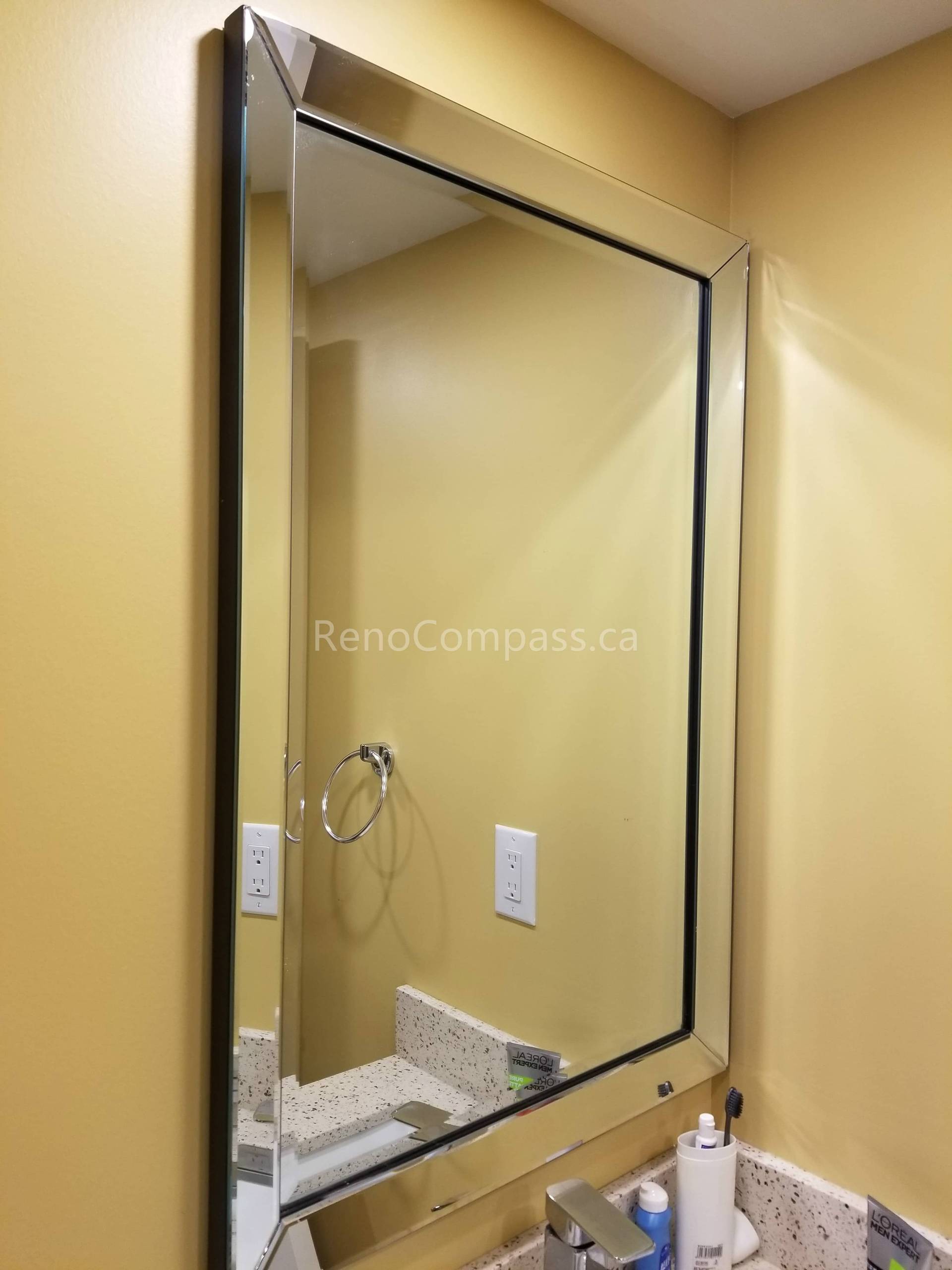 This Vaughan basement renovation features a clean and modern bathroom upgrade with a sleek framed vanity mirror and updated sink area. The bright wall color, stone countertop, and refined mirror installation enhance lighting reflection and create a more spacious, functional bathroom environment. Completed by Reno Compass Inc., this basement bathroom improvement adds both style and practicality to the finished living space.