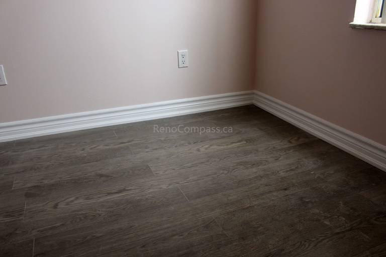 Newly installed dark wood-look luxury vinyl flooring with crisp white baseboards, enhancing the elegance of this Mississauga home renovation. The modern flooring finish blends durability and style, ideal for contemporary interiors.