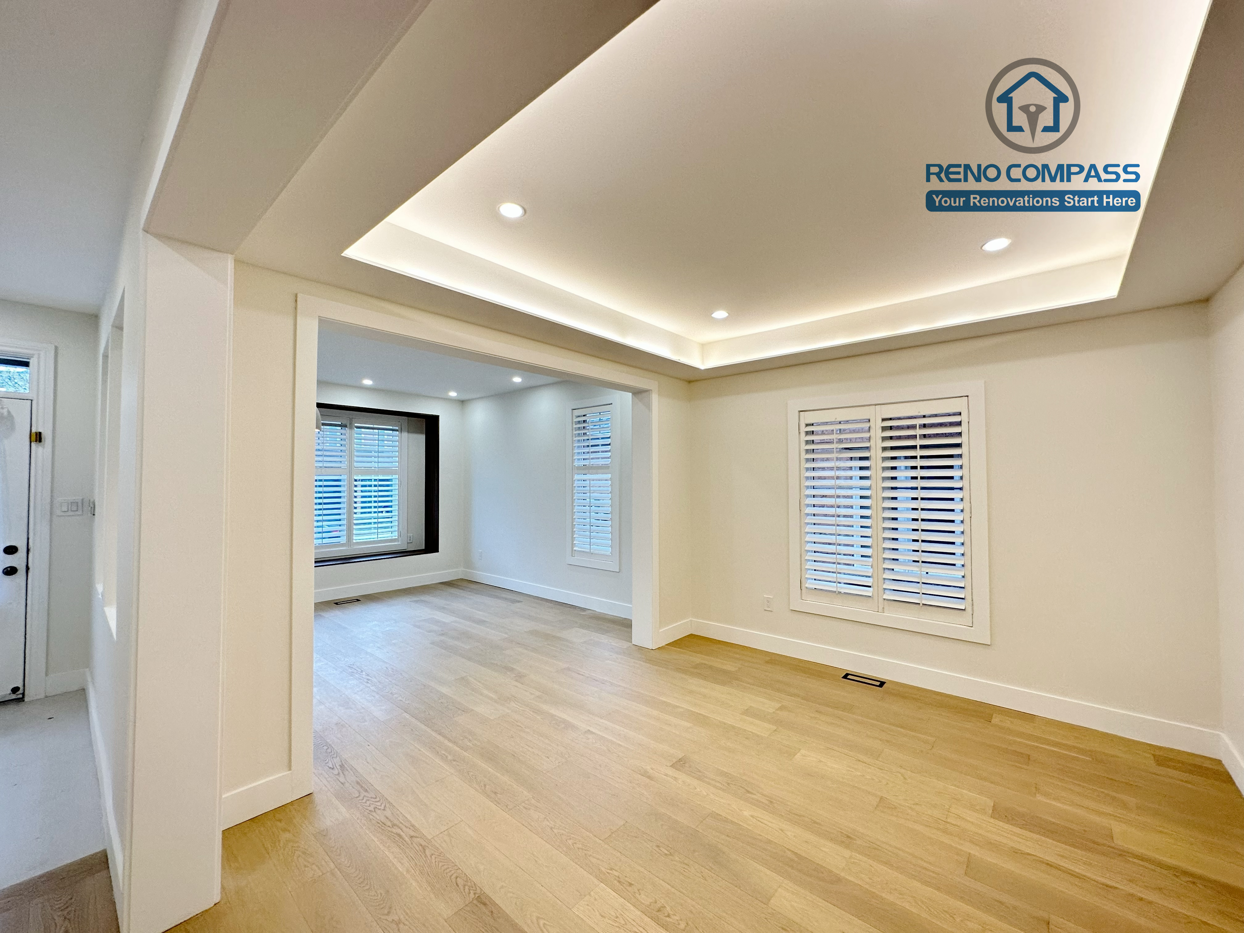 Spacious living area in a Richmond Hill home featuring light-tone hardwood flooring, a modern tray ceiling with recessed lighting, and large windows that enhance brightness and a clean, contemporary interior.