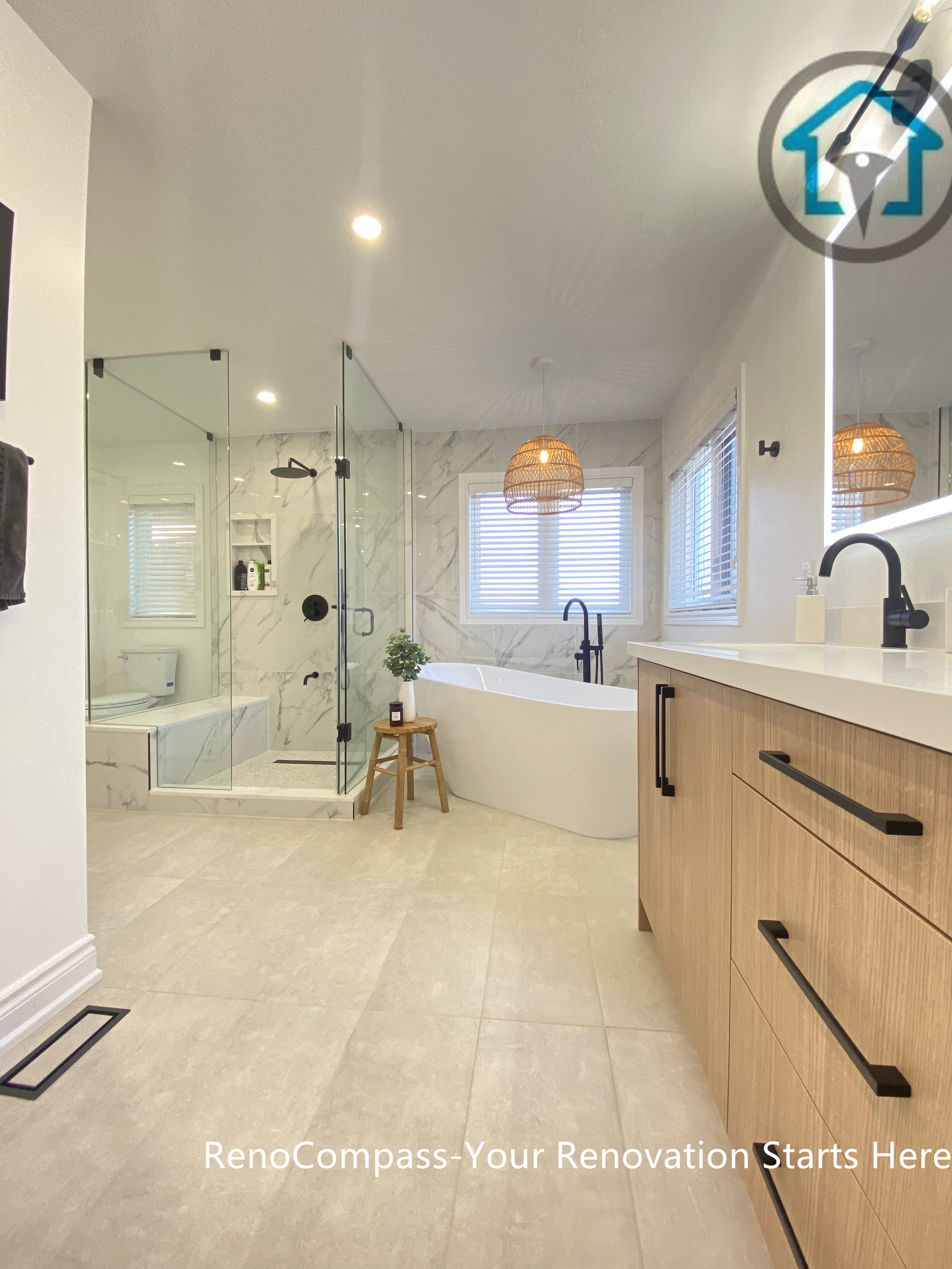 Spacious Oakville bathroom renovation featuring a custom double vanity with wood-tone cabinetry, LED backlit mirrors, a frameless glass walk-in shower, and a freestanding bathtub. This modern bathroom remodel balances functionality, natural light, and clean contemporary design, completed by a professional Toronto renovation company.