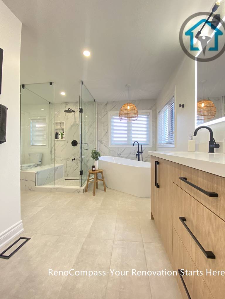 Spacious Oakville bathroom renovation featuring a custom double vanity with wood-tone cabinetry, LED backlit mirrors, a frameless glass walk-in shower, and a freestanding bathtub. This modern bathroom remodel balances functionality, natural light, and clean contemporary design, completed by a professional Toronto renovation company.