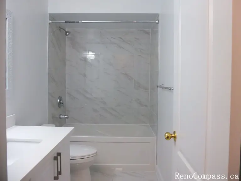 This Richmond Hill bathroom renovation features a clean tub-shower combination with marble-look wall tiles, modern glass doors, and a sleek vanity. Completed by a professional Toronto renovation company, the layout maximizes functionality while maintaining a bright and contemporary aesthetic. Neutral finishes and durable materials create a fresh, low-maintenance bathroom designed for everyday comfort and long-term use.