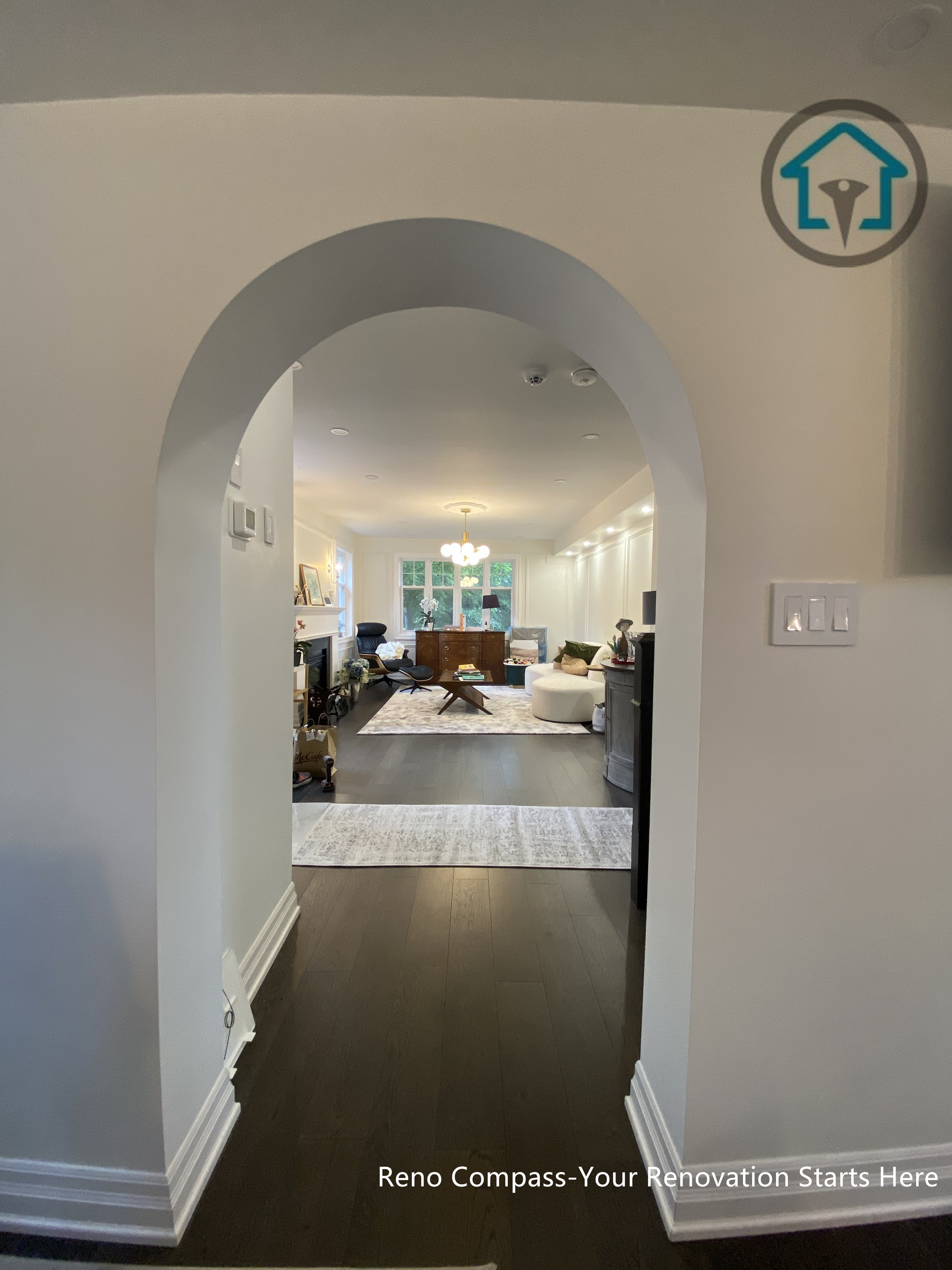 This interior renovation in Toronto features a softly curved arched entryway that frames the transition between spaces while guiding the main sightline toward the living area. The arch introduces architectural character without overpowering the interior, creating a subtle sense of arrival and depth. Consistent flooring and neutral wall finishes help maintain visual continuity, allowing the open layout beyond to feel connected yet clearly defined. This design detail enhances flow, proportion, and the overall spatial experience of the home.
