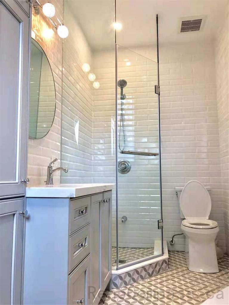 This North York bathroom renovation showcases a guest bathroom featuring a glass shower enclosure, custom vanity with integrated storage, white subway wall tiles, and patterned tile flooring. The layout is designed to maximize space efficiency while maintaining a bright, clean, and functional bathroom environment.