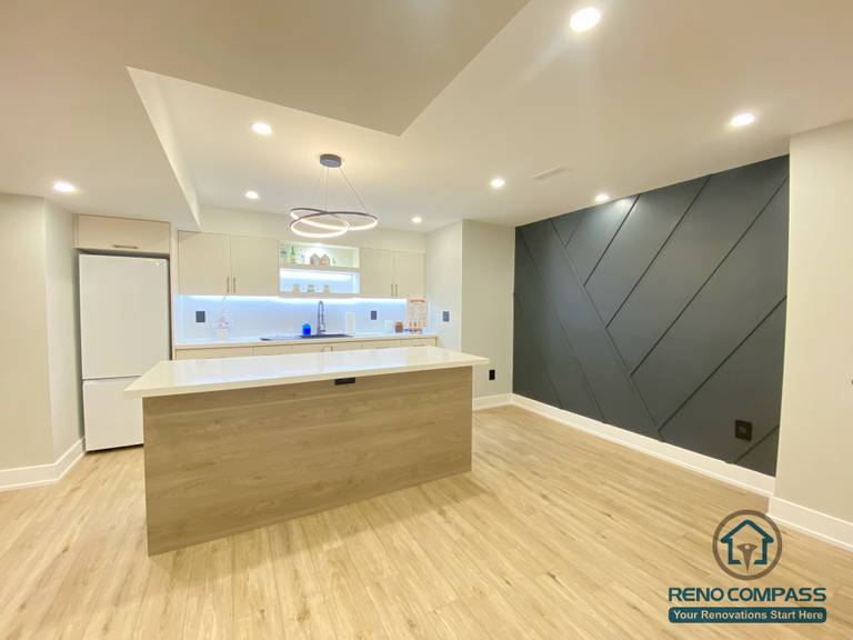 This Aurora basement renovation features a modern open-concept layout with a custom kitchen island, wood-tone cabinetry, integrated LED lighting, and clean contemporary finishes. Designed to maximize brightness and functionality, the space blends living, dining, and kitchen areas seamlessly, creating a comfortable and practical lower-level living environment. Completed by a Toronto renovation company, this basement renovation demonstrates thoughtful space planning and modern design execution.