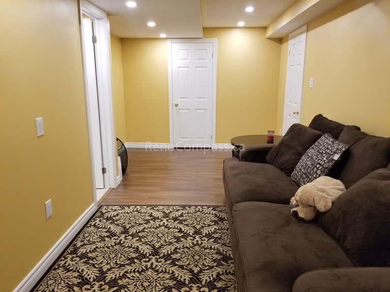 This Vaughan basement renovation showcases a refreshed living area with newly installed wood-look flooring, updated lighting, and a functional layout that connects multiple rooms seamlessly. The warm wall tones and durable flooring create a comfortable and inviting basement environment suitable for relaxation, entertainment, or extended living space. Completed by Reno Compass Inc., this basement upgrade enhances both practicality and modern appeal for everyday use.
