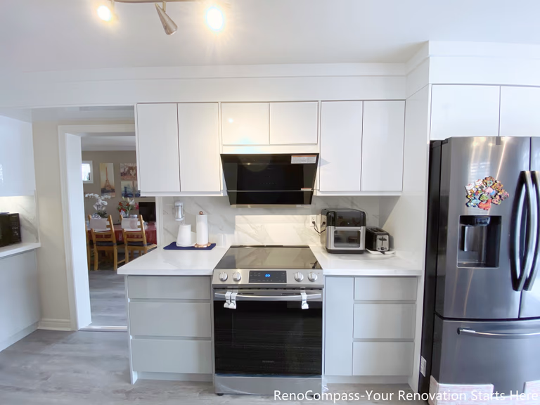 This image presents a modern kitchen renovation in Mississauga featuring full-height white cabinetry, integrated upper storage, and a clean appliance wall layout. The kitchen includes a stainless steel range, built-in hood, quartz countertops, and energy-efficient appliances, creating a balanced mix of functionality and visual clarity. Consistent cabinetry lines and neutral finishes improve workflow and storage efficiency, while the open layout supports everyday cooking and family use. This design reflects a practical and timeless approach to Mississauga kitchen renovations.