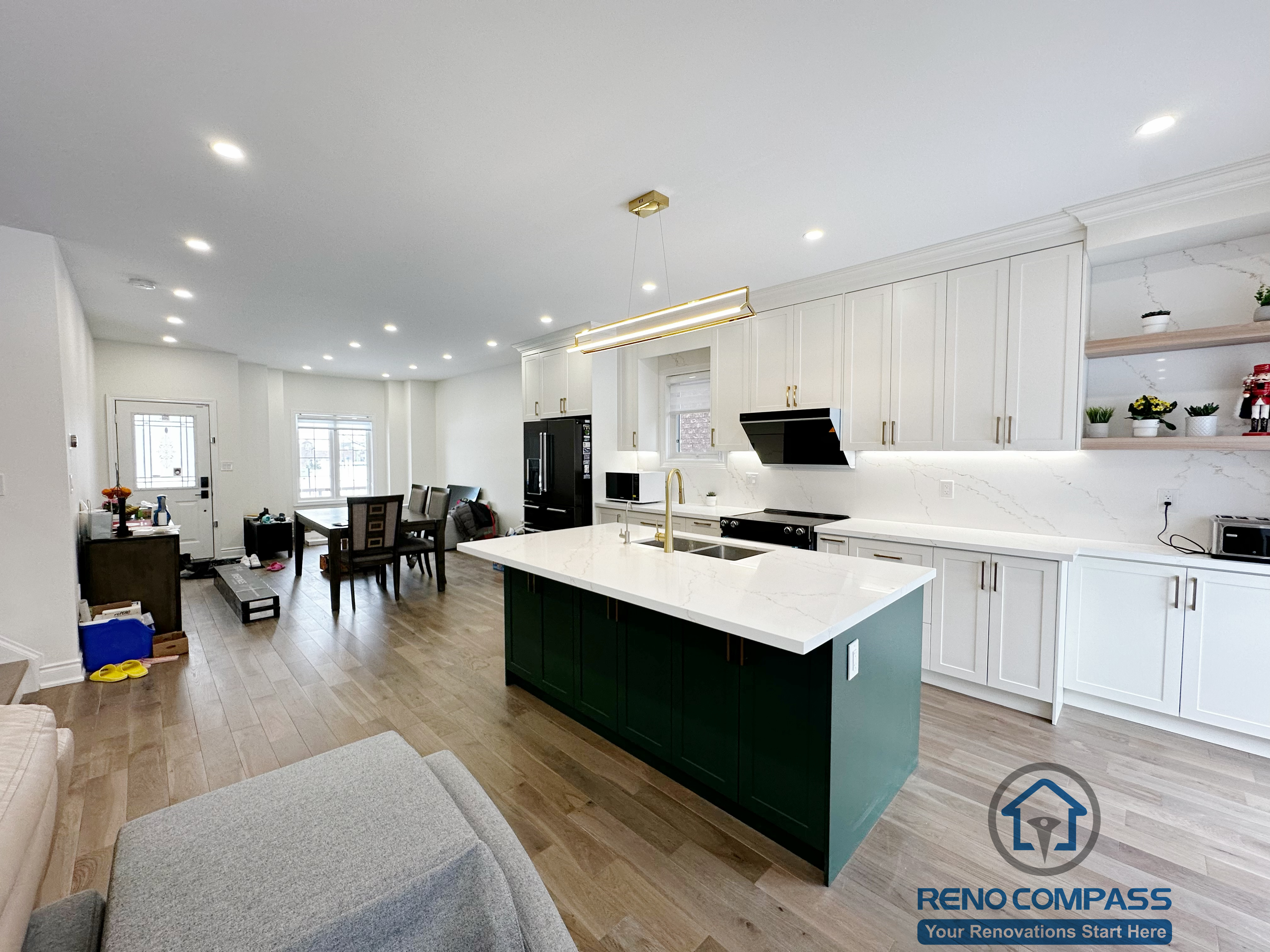 Open-concept interior renovation in Markham featuring a modern kitchen with white cabinetry, quartz countertops, a contrasting green island, and seamless connection to the living area. The layout improves circulation, natural light, and everyday functionality.