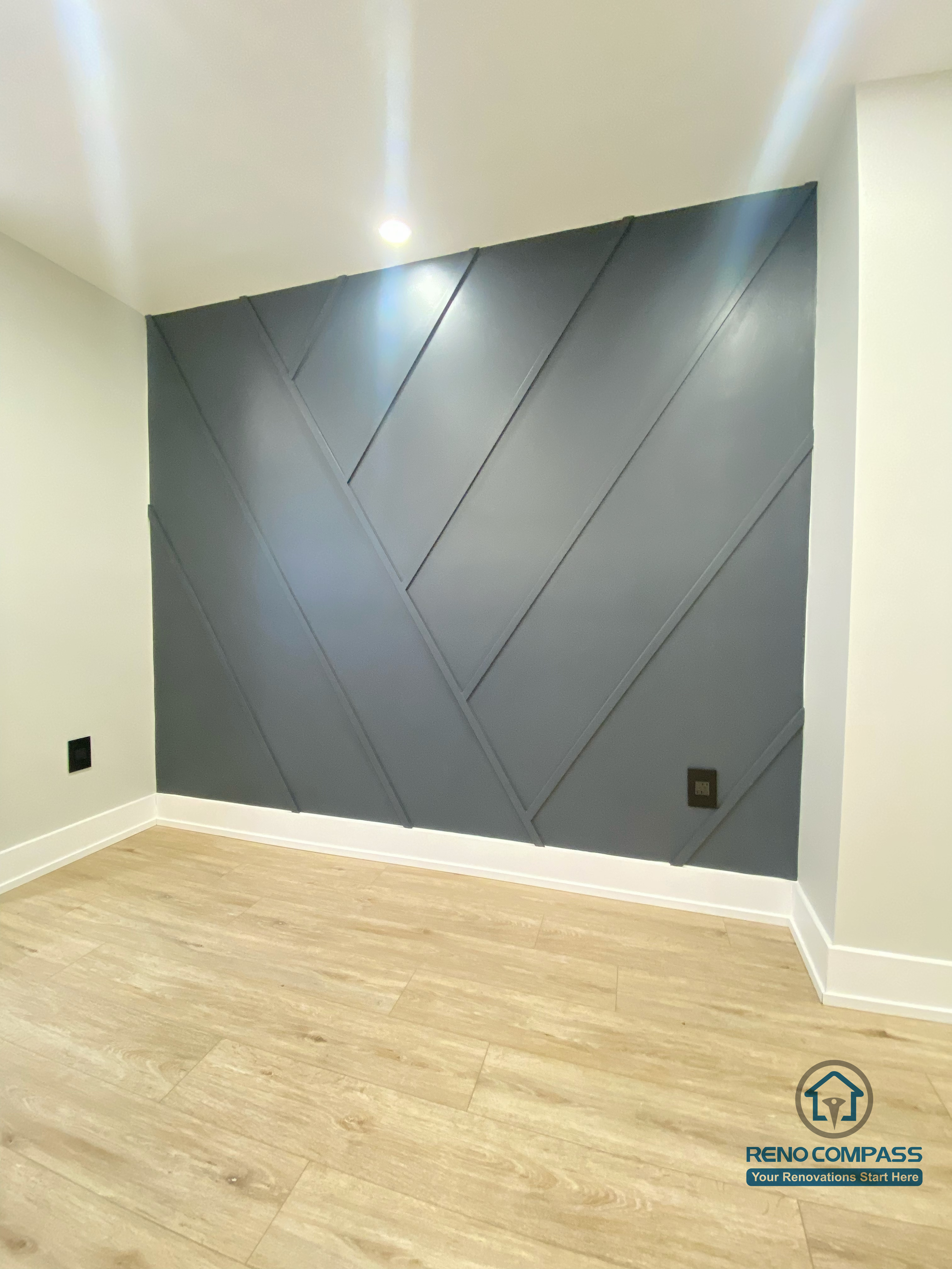 This Aurora basement renovation features a custom geometric accent wall that adds depth, texture, and a modern architectural character to the space. The clean-lined wall design pairs with wood-look flooring and recessed ceiling lighting to create a refined yet visually engaging basement interior. Completed by a Toronto renovation company, this project highlights detailed craftsmanship and contemporary design elements tailored for modern basement living.