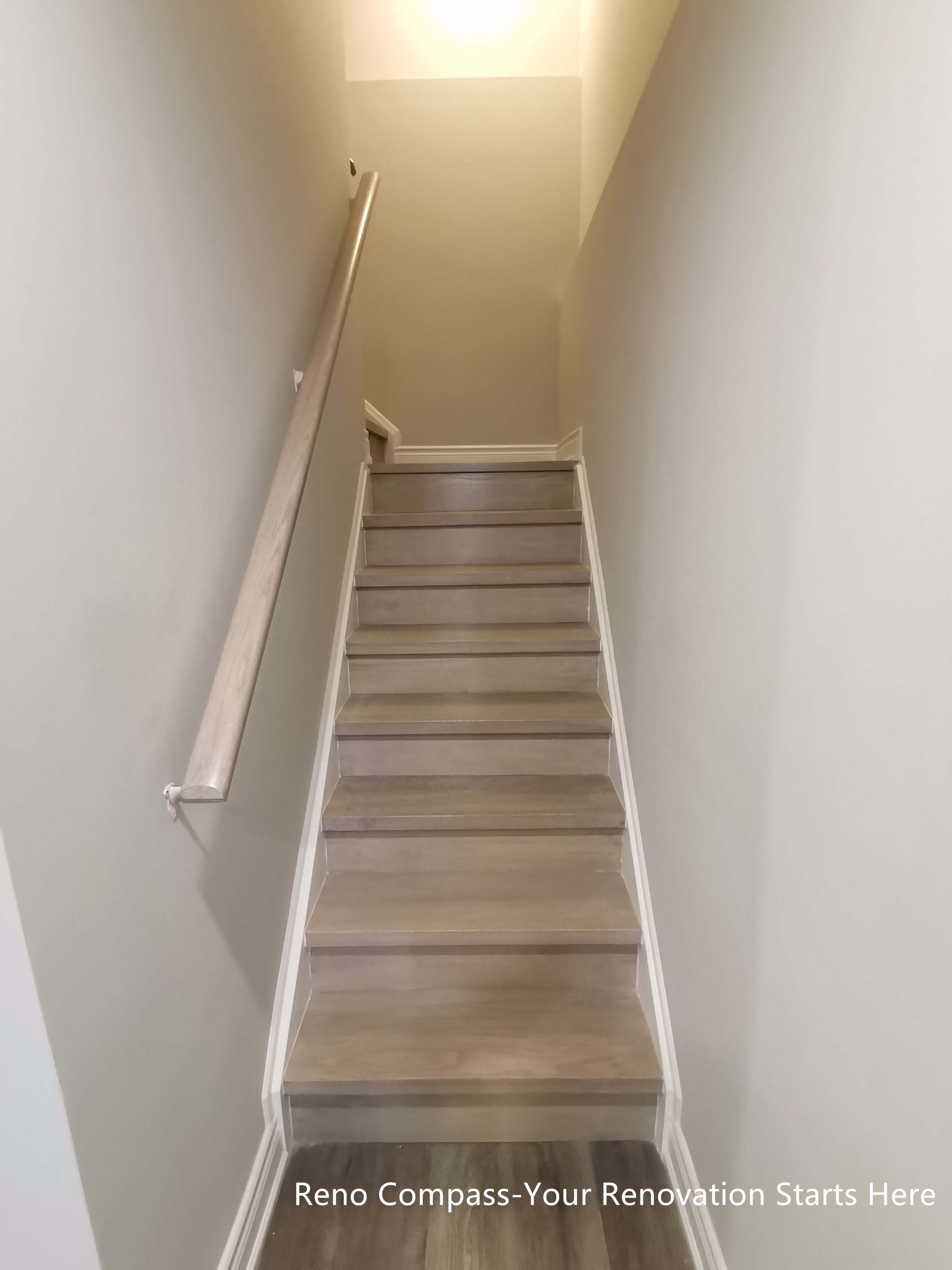 This basement staircase renovation in Vaughan features modern wood steps with clean white wall finishes and a streamlined handrail design. The staircase provides a smooth and comfortable transition between levels while maintaining visual consistency with the overall basement renovation. Thoughtful lighting and proportion ensure the stairwell feels bright and uncluttered rather than enclosed. Designed and completed by Reno Compass, this staircase renovation emphasizes safety, durability, and cohesive interior flow.