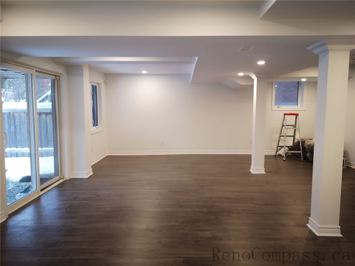 This Richmond Hill basement renovation showcases a spacious open-concept layout with newly installed dark wood flooring, pot lights, and clean modern finishes. Structural columns were integrated seamlessly into the design to maintain an open and functional living space. The upgraded lighting and neutral wall tones create a warm and inviting basement environment ideal for family use or entertainment. Completed by a professional Toronto renovation company, Reno Compass Inc., this finished basement delivers both comfort and contemporary style.