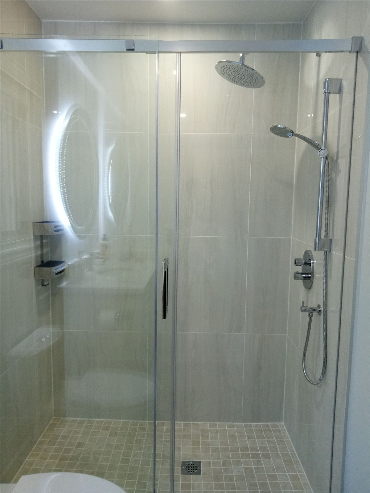 This bathroom renovation in Richmond Hill highlights a frameless glass shower enclosure with large-format wall tiles, mosaic shower flooring, and modern rainfall shower fixtures. The clean tile layout and transparent glass design enhance both visual openness and daily comfort. As part of a complete interior renovation, this shower upgrade reflects precise installation and durable material selection completed by a professional Toronto renovation company serving Richmond Hill homeowners.