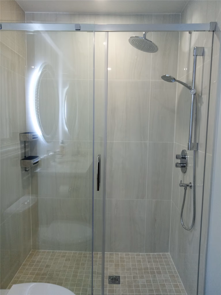 This bathroom renovation in Richmond Hill highlights a frameless glass shower enclosure with large-format wall tiles, mosaic shower flooring, and modern rainfall shower fixtures. The clean tile layout and transparent glass design enhance both visual openness and daily comfort. As part of a complete interior renovation, this shower upgrade reflects precise installation and durable material selection completed by a professional Toronto renovation company serving Richmond Hill homeowners.