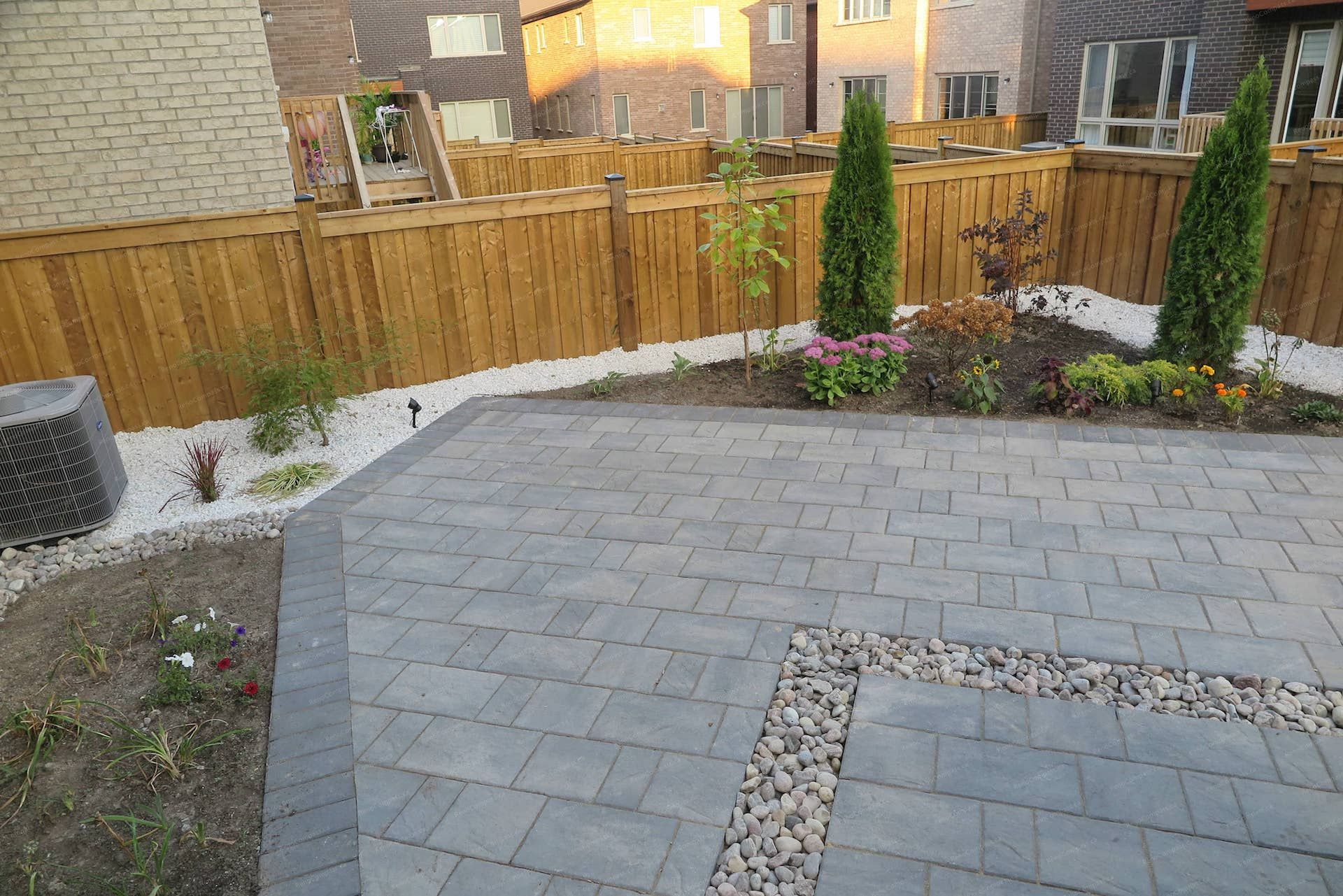 This Vaughan backyard landscaping project features a professionally installed interlock patio with decorative stone accents and thoughtfully designed garden beds. The layout combines durable paving, river rock details, and seasonal plants to create a modern and low-maintenance outdoor living space. Completed with precision and landscaping expertise by Reno Compass Inc. 🌿🏡