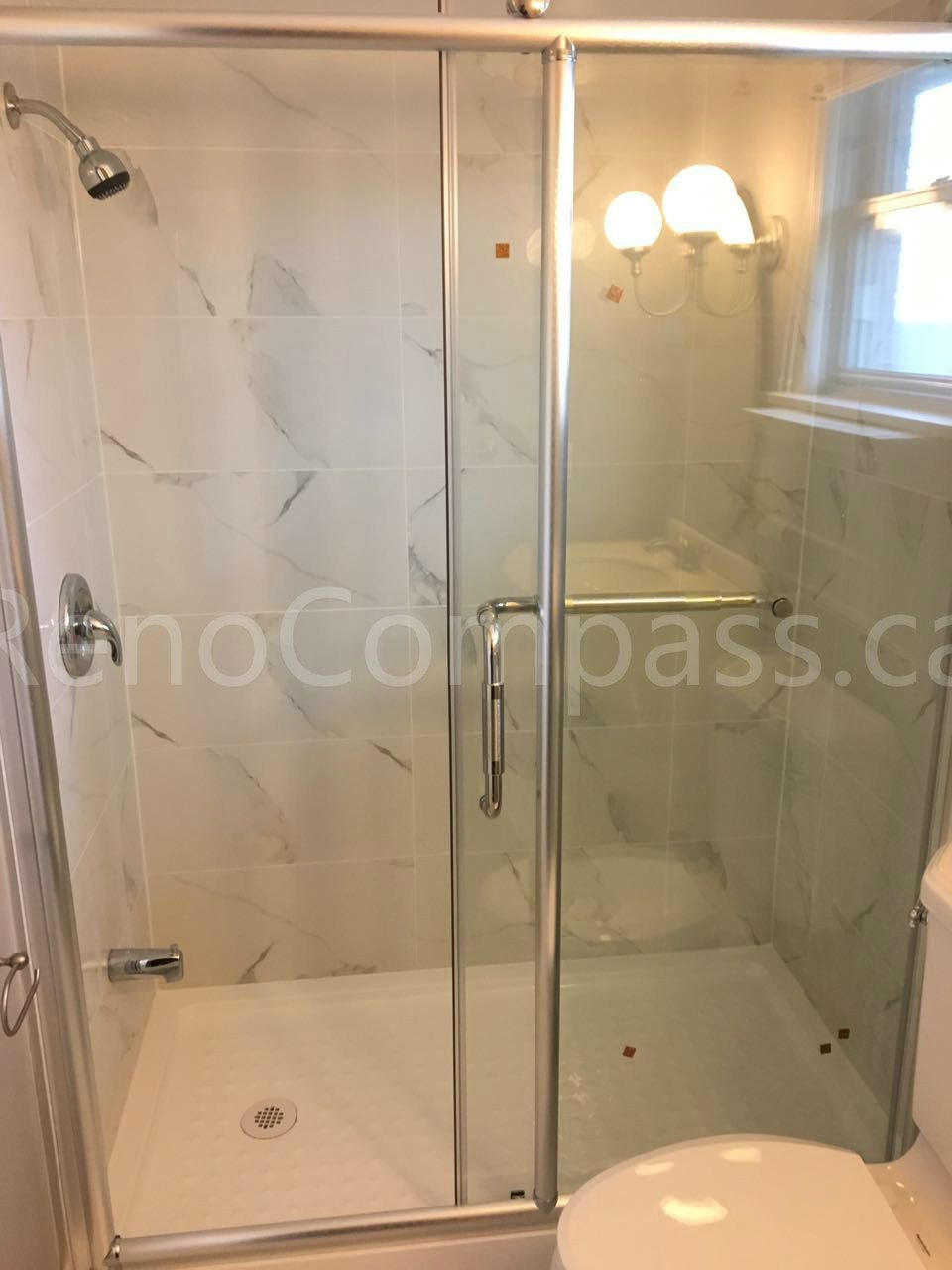 This Mississauga interior renovation showcases a modern bathroom upgrade featuring a frameless glass shower enclosure, marble-style wall tiles, and updated lighting fixtures. Completed by a professional Toronto renovation company, the design enhances brightness, functionality, and everyday comfort while delivering a clean, contemporary look with durable, easy-to-maintain finishes.