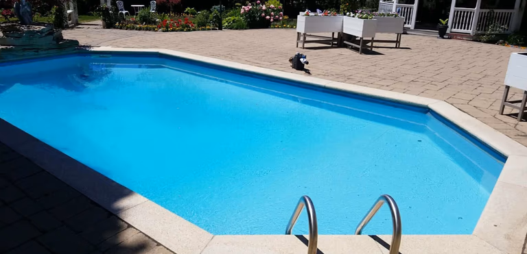 After renovation photo of a fully restored backyard swimming pool in Toronto. The new bright blue liner, clean water, and resurfaced edges highlight the professional pool transformation from old and damaged to modern and inviting. Expert pool renovation by local Toronto specialists.