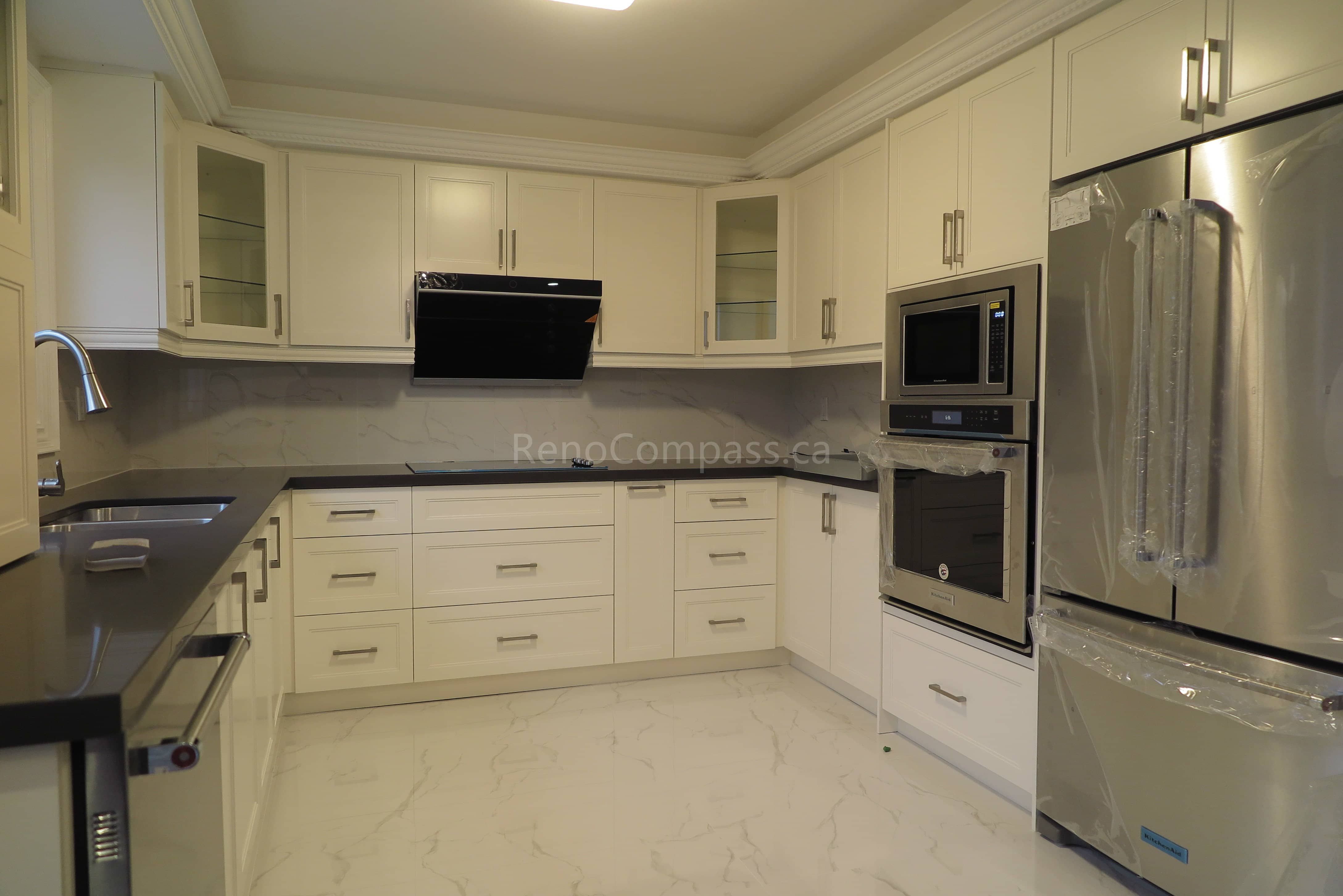 This Markham kitchen renovation features custom white shaker cabinets, modern quartz countertops, and a clean L-shaped layout designed for functionality and style. The kitchen is equipped with built-in stainless steel appliances, under-cabinet storage solutions, and sleek hardware that enhances both efficiency and aesthetics. Bright finishes and crown molding details create a timeless and elegant cooking space. Completed by Reno Compass, a professional renovation contractor specializing in kitchen renovations and full interior remodeling across Markham and the Greater Toronto Area.