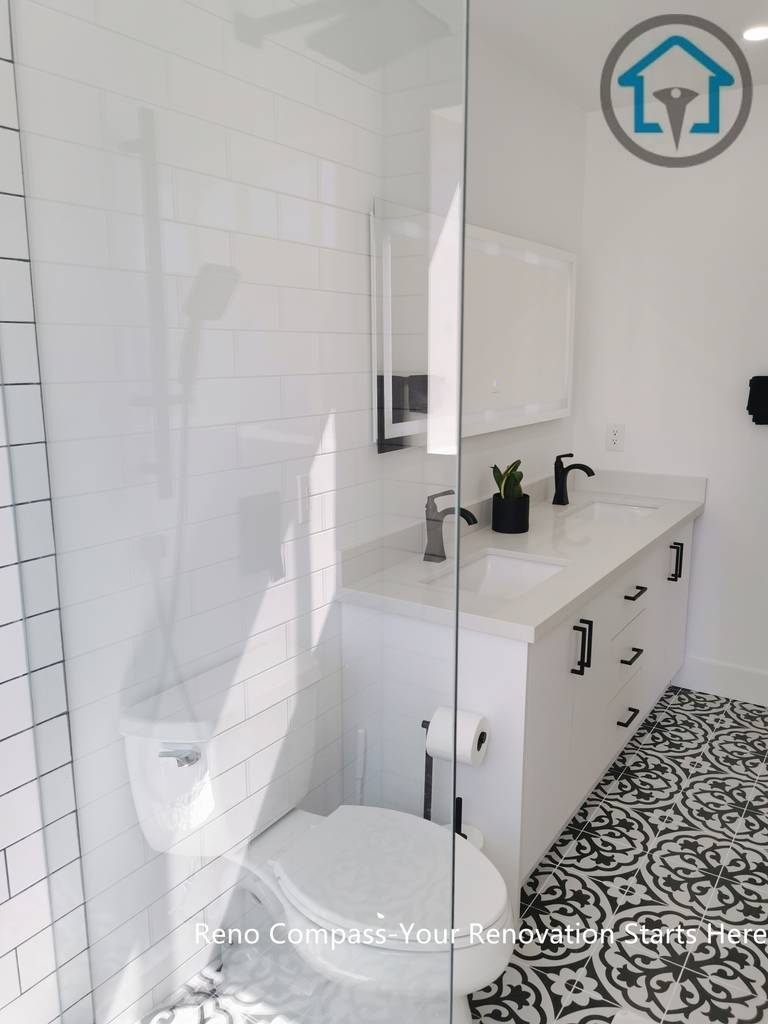 This Ajax bathroom renovation features a clean and timeless design with a white double-sink vanity, matte black fixtures, and a glass-enclosed shower. The patterned tile floor adds visual character while keeping the overall space bright, functional, and easy to maintain—perfect for modern family living.