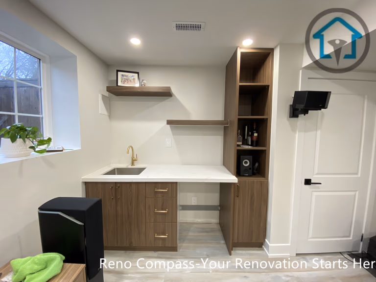 This Stouffville basement renovation features a modern kitchenette with custom wood cabinetry, quartz countertop, integrated sink, open shelving, and built-in storage. Designed and built by Reno Compass Inc., this basement upgrade enhances functionality and adds long-term value with clean lines and efficient space planning.