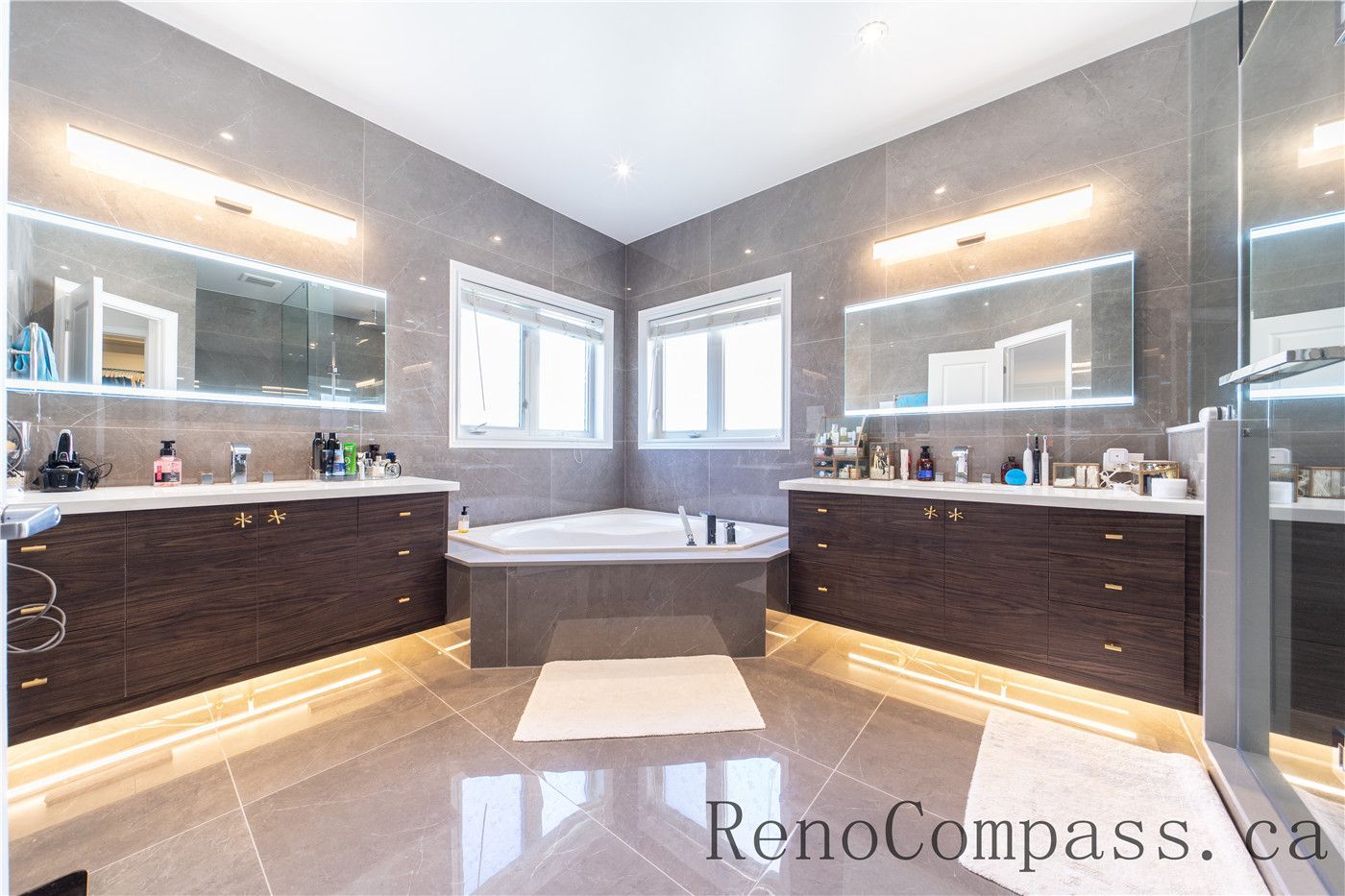 This Richmond Hill entire house interior renovation features a spacious luxury master bathroom with a double vanity, modern LED mirrors, and a central soaker tub. Large-format tiles, custom cabinetry, and under-cabinet lighting create a bright and sophisticated spa-like atmosphere. Completed by a trusted Toronto renovation company, this bathroom renovation combines elegance, functionality, and high-end finishes to enhance comfort and home value.