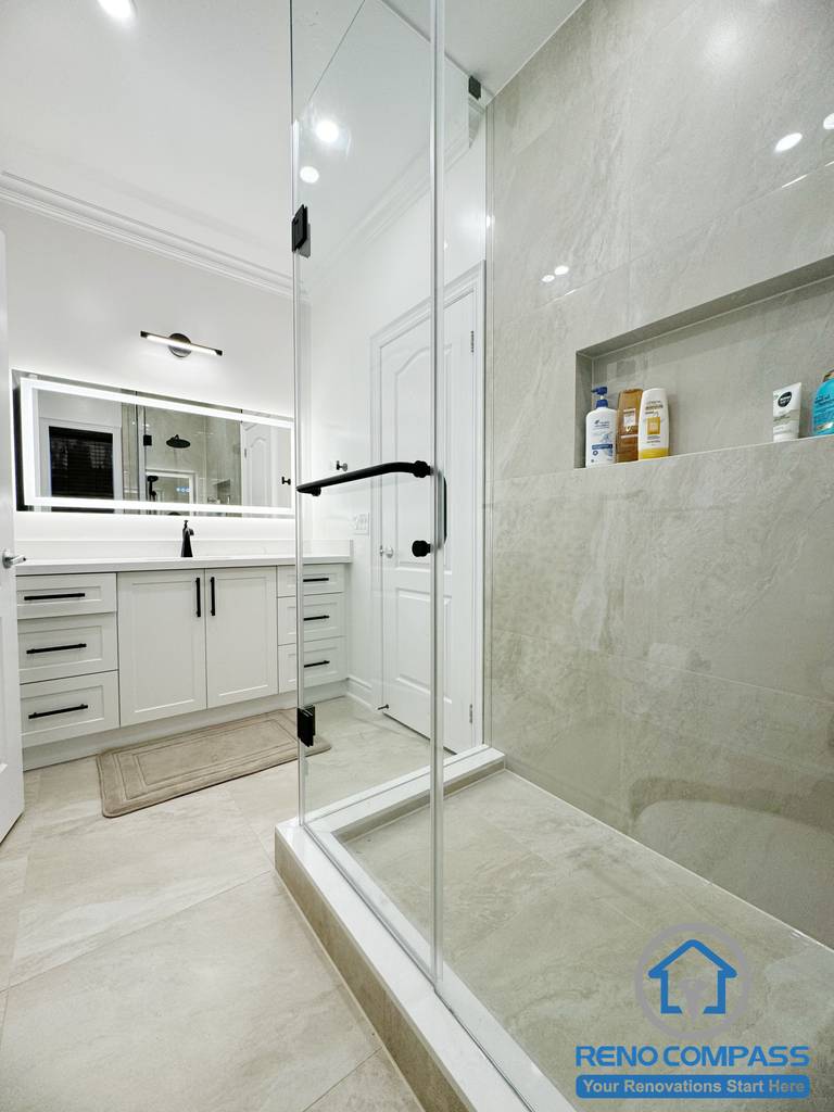 This Vaughan bathroom renovation presents a complete spa-inspired layout featuring a frameless glass shower, freestanding bathtub, and custom double vanity with quartz countertops. Large-format marble-look tiles, matte black fixtures, and integrated lighting create a bright, cohesive, and modern atmosphere. Completed by an experienced Toronto Renovation Company, this bathroom design emphasizes comfort, functionality, and clean contemporary craftsmanship.