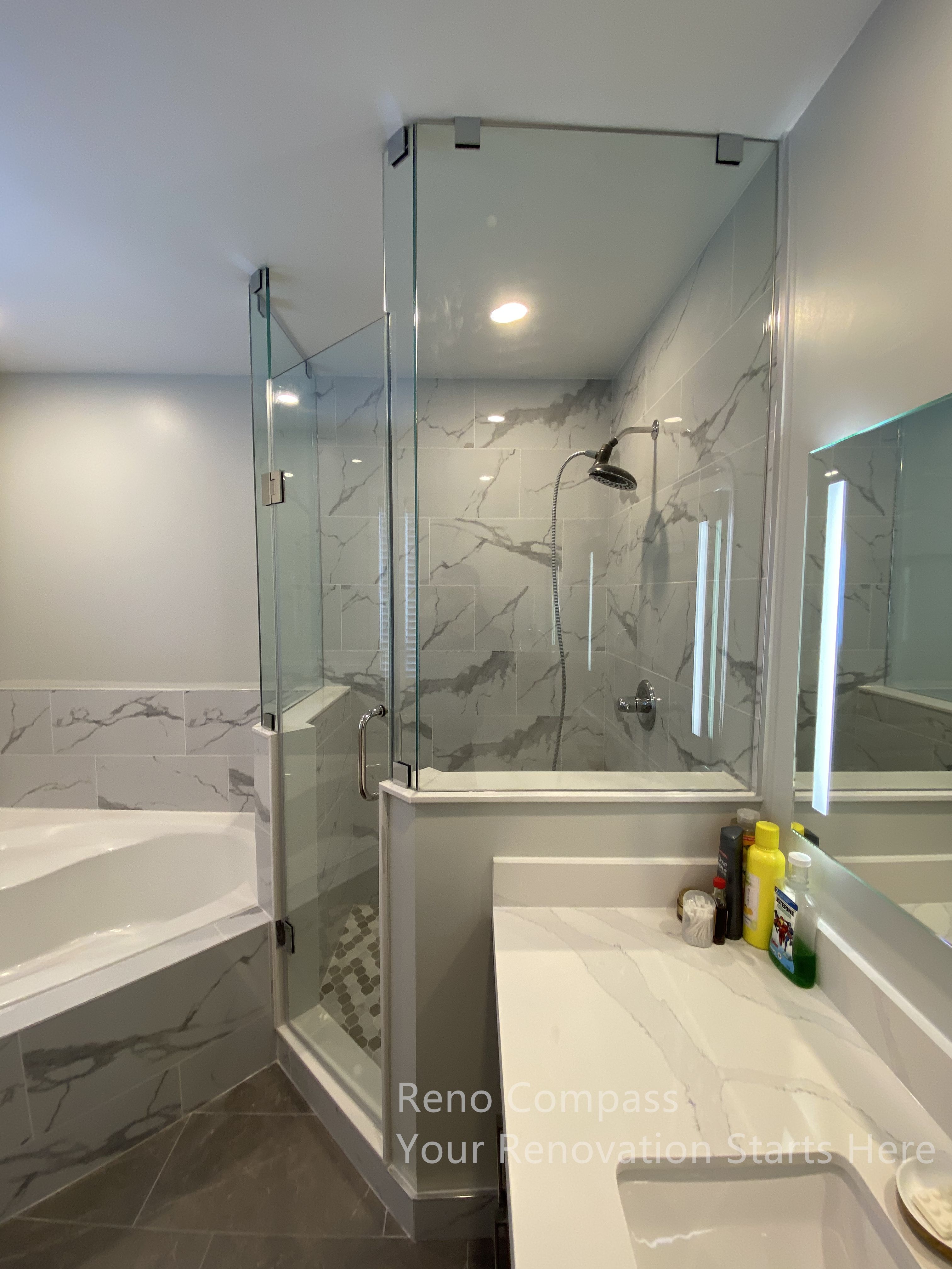 This Newmarket bathroom renovation highlights a frameless glass shower enclosure paired with marble-look wall tiles and a clean-lined vanity countertop. The transparent glass panels enhance openness and allow light to flow naturally throughout the space, while the tiled shower walls and durable flooring provide long-term moisture resistance. A streamlined vanity surface offers practical daily use without visual clutter, reinforcing a calm and modern aesthetic. The overall layout balances functionality and visual clarity, creating a bright, spa-inspired bathroom designed for everyday comfort, completed by Reno Compass.