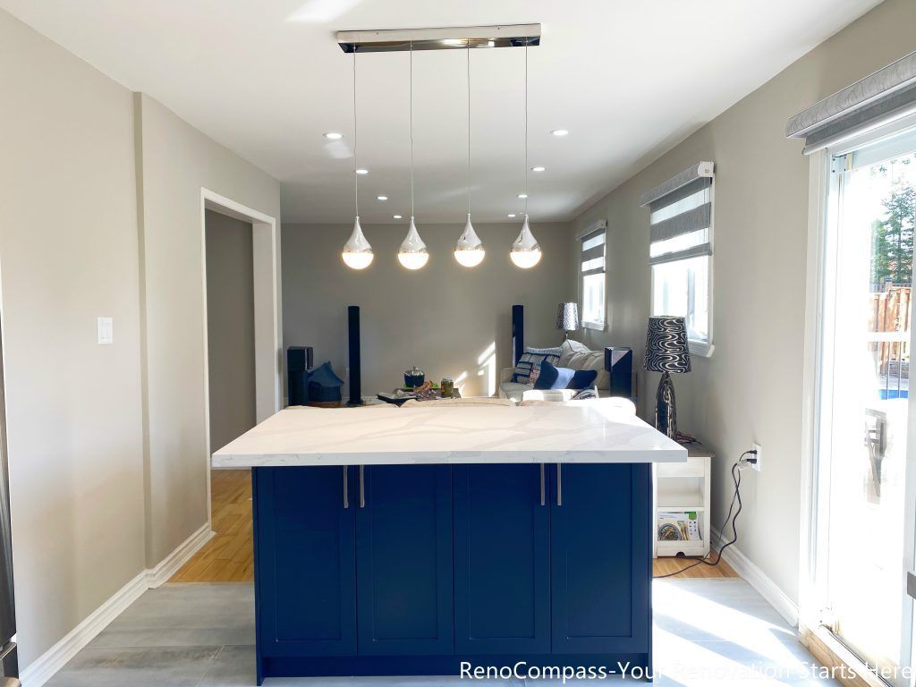 A central kitchen island from a Newmarket interior renovation, featuring quartz countertops, deep blue cabinetry, and modern pendant lighting that enhances the open-concept layout by a Toronto renovation company.