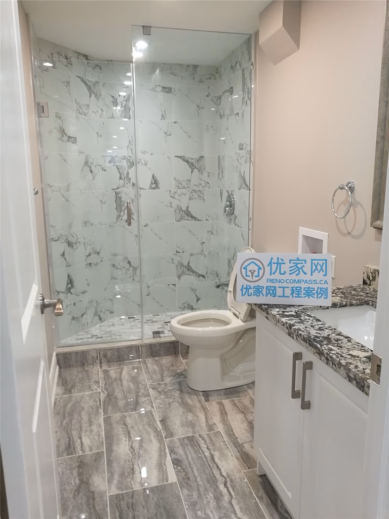 Modern basement bathroom renovation in Richmond Hill featuring a frameless glass shower, marble-look wall tiles, stone-finish floor tiles, custom vanity, and updated lighting. This basement bathroom remodel improves functionality, moisture protection, and overall space efficiency, completed by a professional Toronto renovation company.