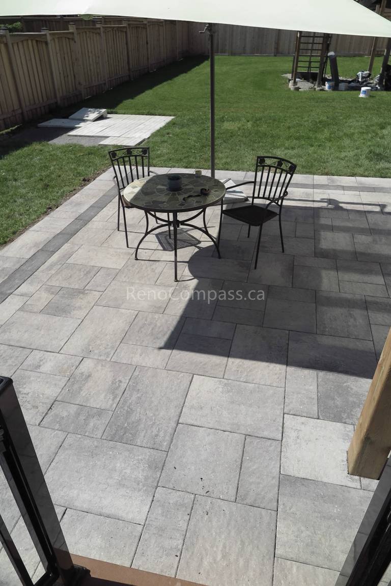 This Markham backyard landscaping project highlights a professionally installed interlock stone patio with a modern rectangular pattern and contrasting border design. The clean layout provides a spacious outdoor seating area ideal for dining and relaxation. Built for durability and low maintenance, the patio enhances both functionality and visual appeal while seamlessly connecting the home to the backyard lawn. Completed by Reno Compass, this project delivers a refined and practical outdoor living space for everyday enjoyment and summer gatherings.