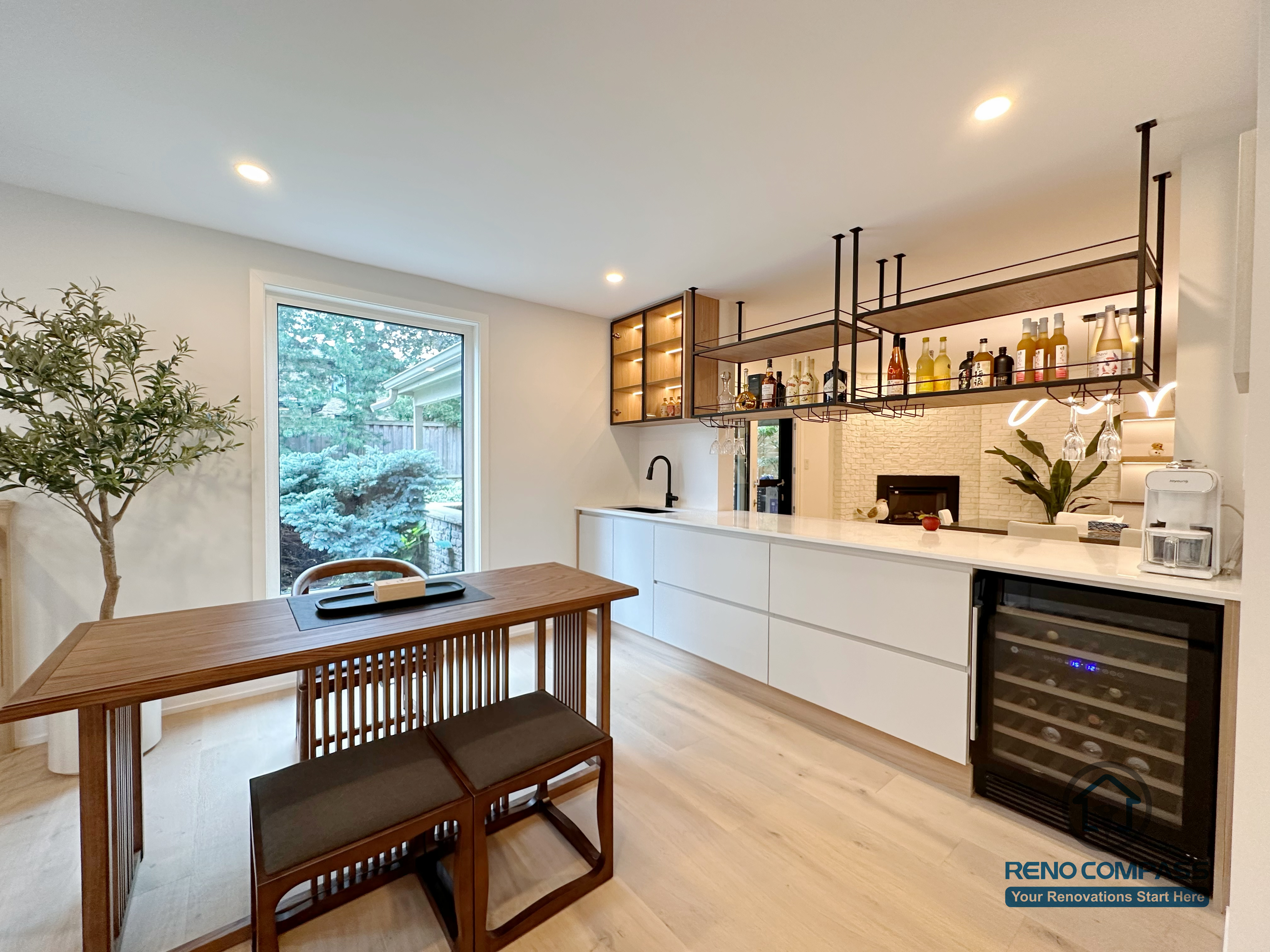 An open-concept kitchen and dining area renovation in Toronto featuring custom cabinetry, a built-in bar and beverage station, and clean-lined storage design. Warm wood flooring, integrated lighting, and seamless circulation create a functional yet elegant living space, completed by a professional Toronto renovation company.