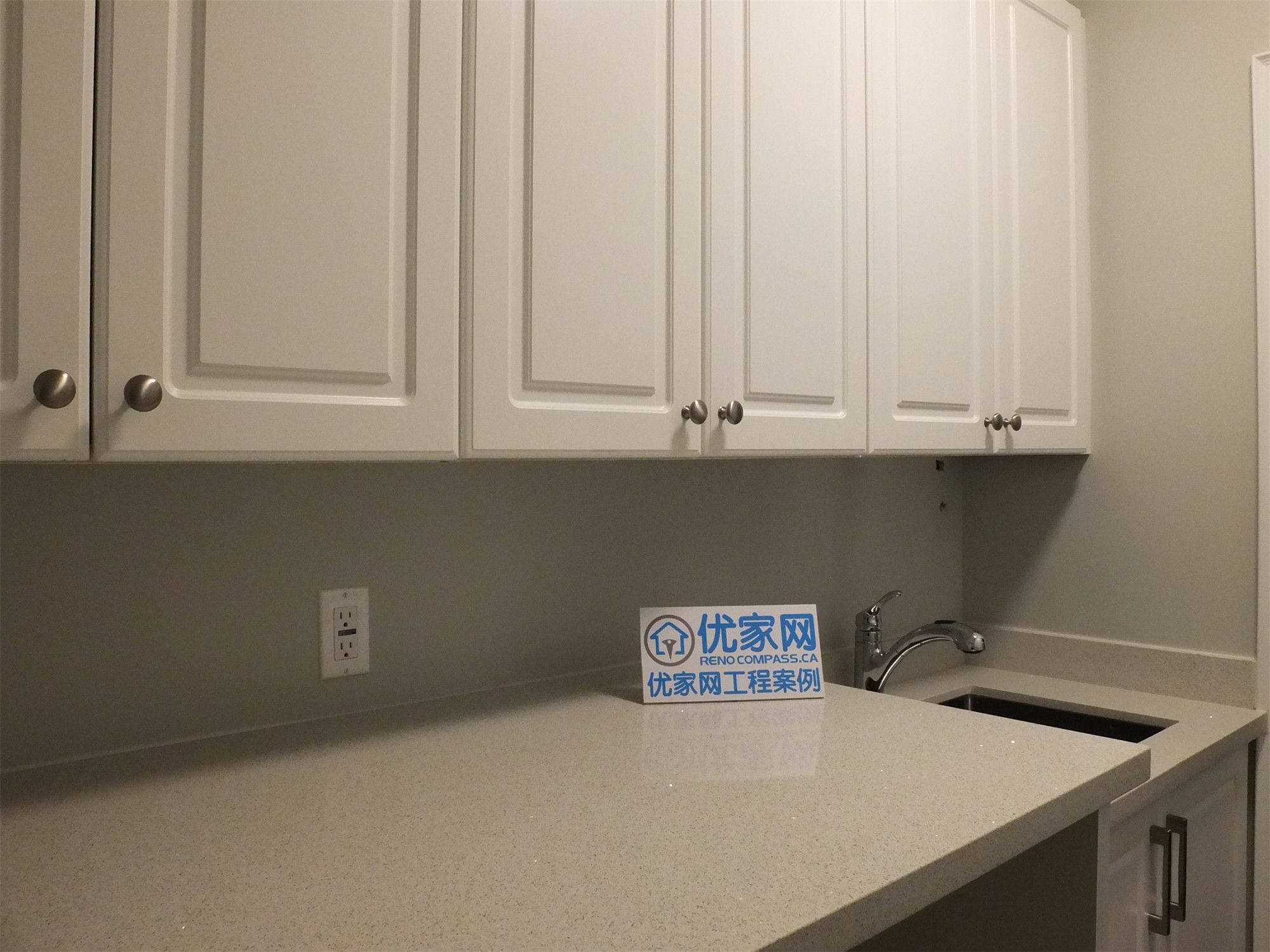 This Richmond Hill basement renovation highlights a detailed view of the utility area, featuring a quartz countertop, custom upper cabinets, and a built-in sink. The clean finishes and practical layout provide efficient storage and workspace, ideal for laundry or additional household use.