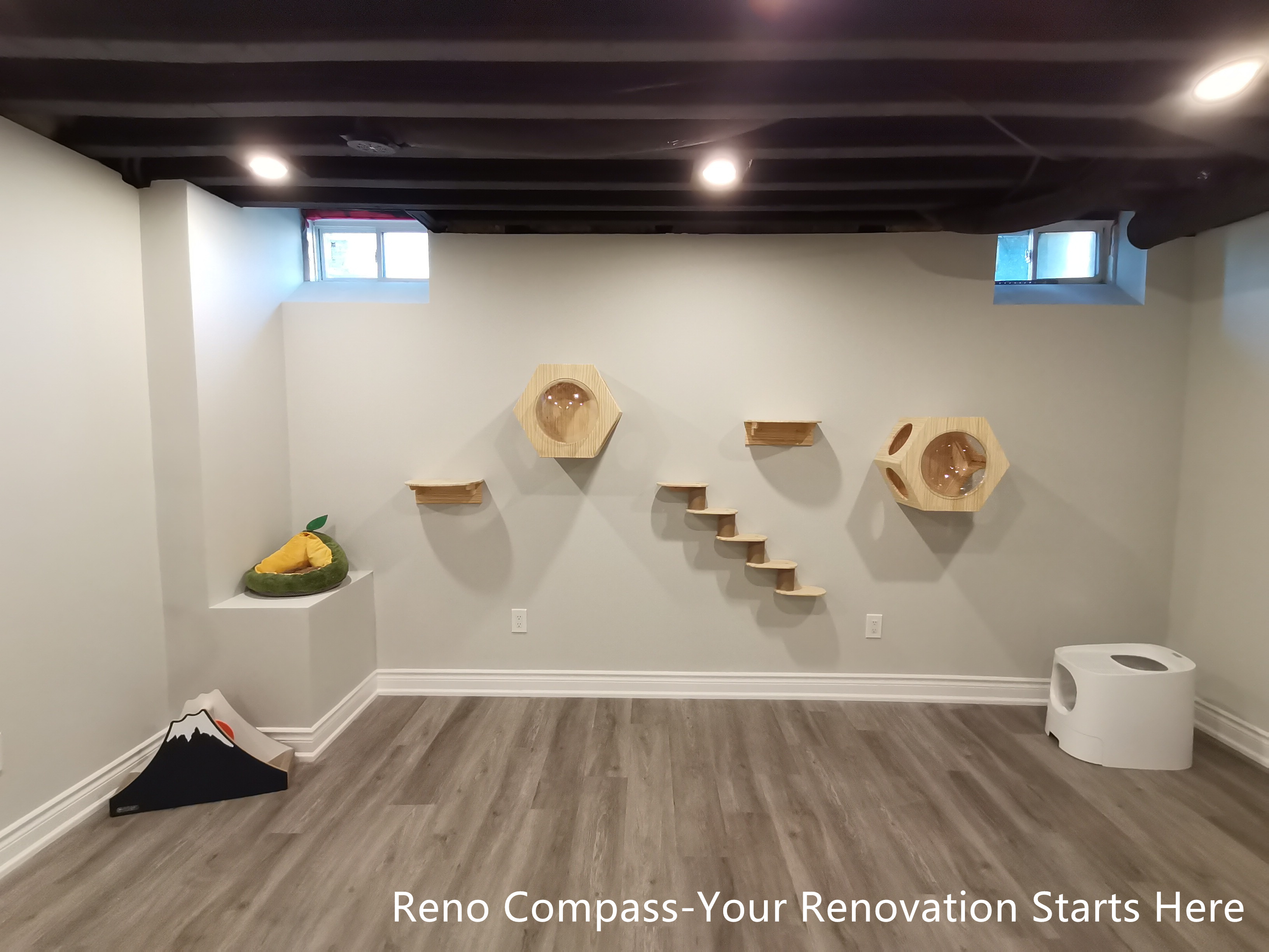 This Vaughan basement renovation features a dedicated cat activity wall integrated into an industrial-style interior with a sprayed black open ceiling and recessed lighting. Custom wall-mounted platforms and climbing elements are arranged with clear spacing and symmetry, allowing pets to move freely while preserving a clean and organized visual layout. Durable flooring and neutral wall finishes provide a practical foundation for daily use. Designed and completed by Reno Compass, this renovation demonstrates how pet-friendly features can be seamlessly incorporated into a modern, functional basement space.