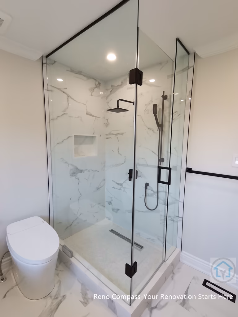 This Thornhill bathroom renovation features a glass-enclosed shower with marble-style wall tiles, modern black fixtures, and a built-in niche for storage. The clean layout integrates the shower area seamlessly with the rest of the bathroom, creating a bright, functional, and well-balanced space for everyday use.