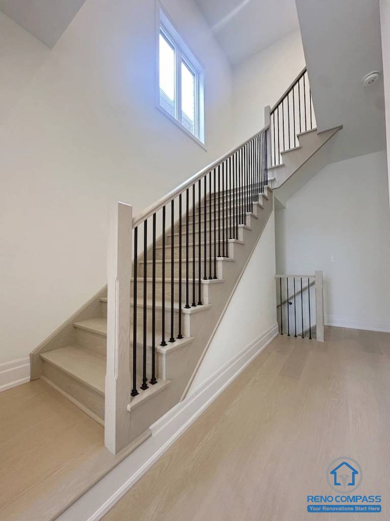 Modern staircase with wood flooring and black metal railings in a Toronto new home upgrade, creating a clean, cohesive look with improved space flow.