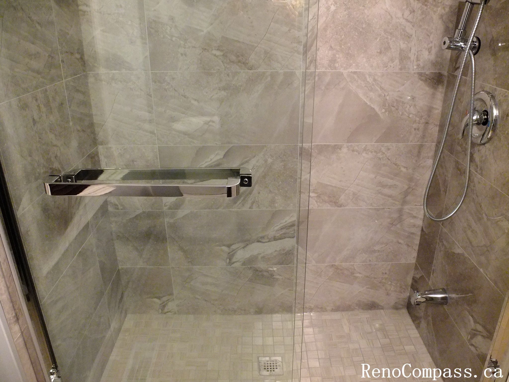 Stylish bathroom renovation in Richmond Hill featuring a frameless glass shower enclosure, marble-look tile walls, and a sleek handheld shower system. Elegant, contemporary design crafted by RenoCompass.ca for a luxurious home update.