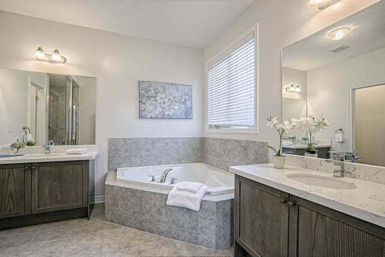 This Toronto luxury master bathroom renovation features a spacious layout with a double vanity, premium stone countertops, and a built-in soaking tub surrounded by elegant tile finishes. The design includes modern lighting, large mirrors, and neutral tones that create a bright and relaxing spa-like environment. Completed by a professional Toronto renovation company, this bathroom project showcases high-quality craftsmanship, functional layout planning, and contemporary residential design tailored for modern comfort.