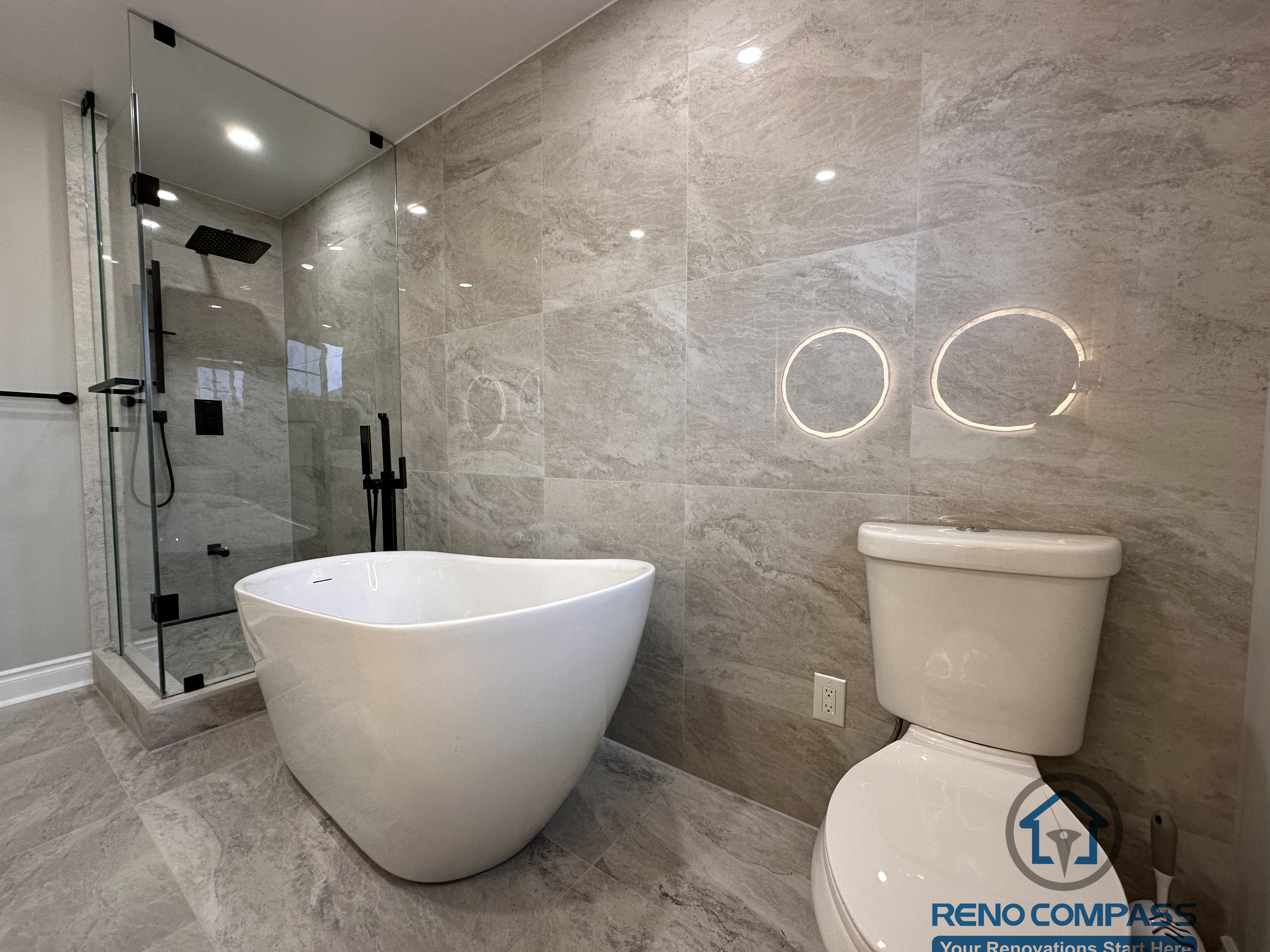 This Markham bathroom renovation features a modern layout with a freestanding bathtub, glass-enclosed shower, and large-format stone-look tiles. Designed and built by a professional Toronto renovation company, Reno Compass Inc., the space balances functionality, clean lines, and long-term durability.