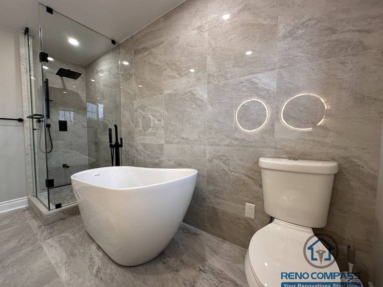 This Markham bathroom renovation features a modern layout with a freestanding bathtub, glass-enclosed shower, and large-format stone-look tiles. Designed and built by a professional Toronto renovation company, Reno Compass Inc., the space balances functionality, clean lines, and long-term durability.