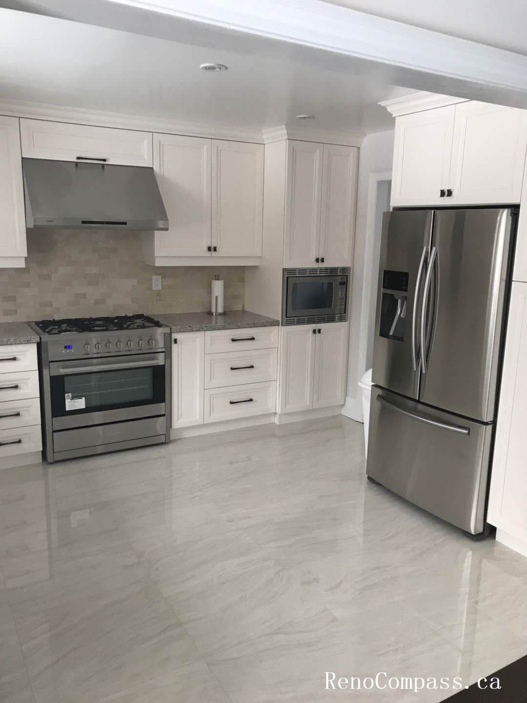 This Markham interior renovation showcases a bright open-concept kitchen featuring custom white cabinetry, stainless steel appliances, and polished porcelain tile flooring. The layout includes a professional-grade gas range with a modern hood fan, built-in microwave, and a full-size stainless steel refrigerator, creating a functional and streamlined cooking space. Neutral mosaic backsplash tiles add subtle texture while maintaining a timeless aesthetic. The clean lines, balanced cabinetry proportions, and durable finishes reflect thoughtful planning and precision installation. This kitchen renovation highlights Reno Compass’ expertise in delivering high-quality interior renovation services across Markham and the Greater Toronto Area.