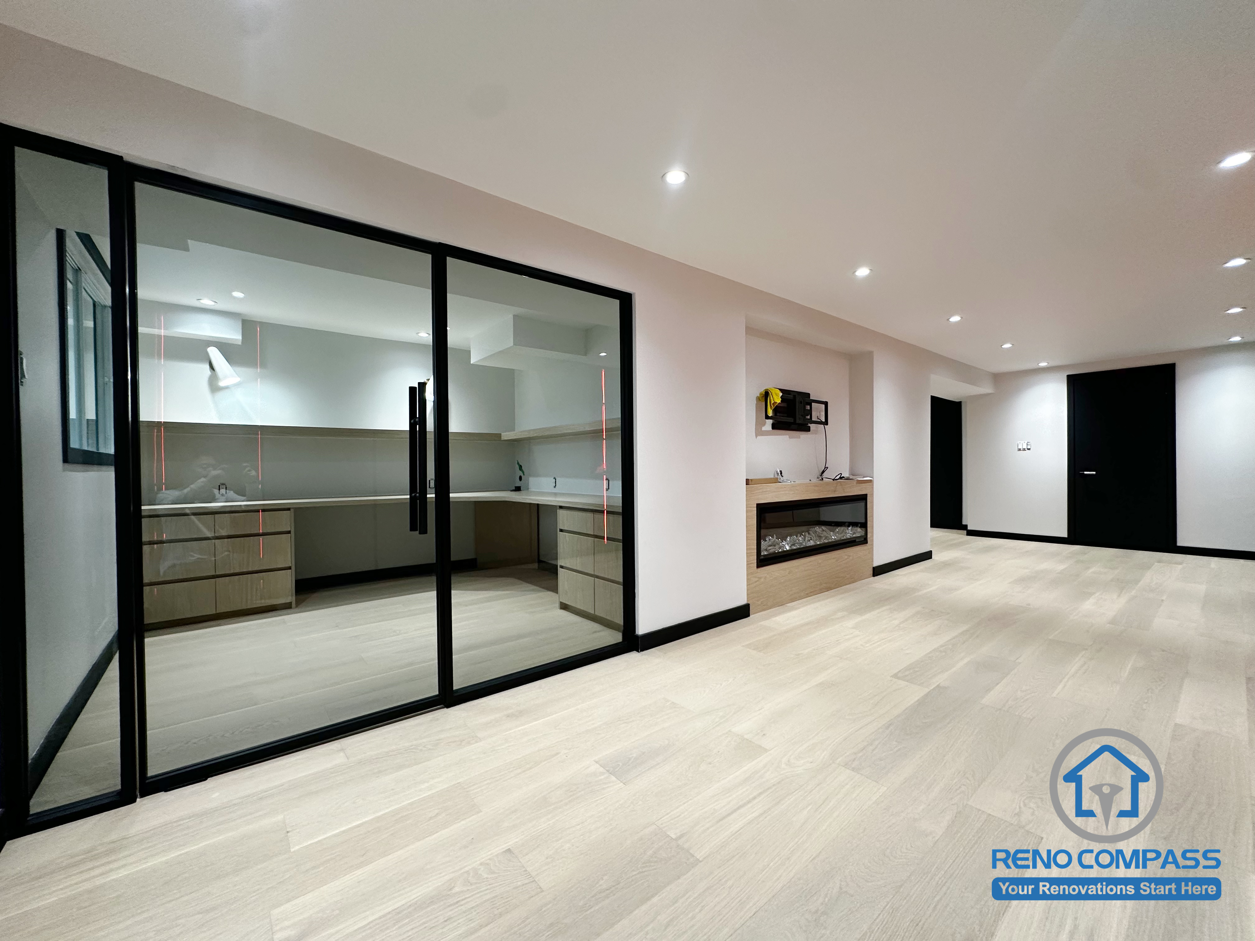 This Richmond Hill basement renovation features a fully glass-enclosed secondary kitchen, providing both openness and practical smoke separation.
The light wood flooring, combined with a sleek built-in modern fireplace and black trim details, creates a clean, contemporary, and comfortable living area.
Perfect as a multifunctional family space with improved layout and storage flow.