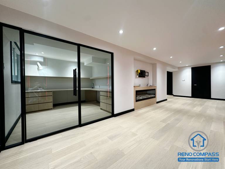 This Richmond Hill basement renovation features a fully glass-enclosed secondary kitchen, providing both openness and practical smoke separation.
The light wood flooring, combined with a sleek built-in modern fireplace and black trim details, creates a clean, contemporary, and comfortable living area.
Perfect as a multifunctional family space with improved layout and storage flow.